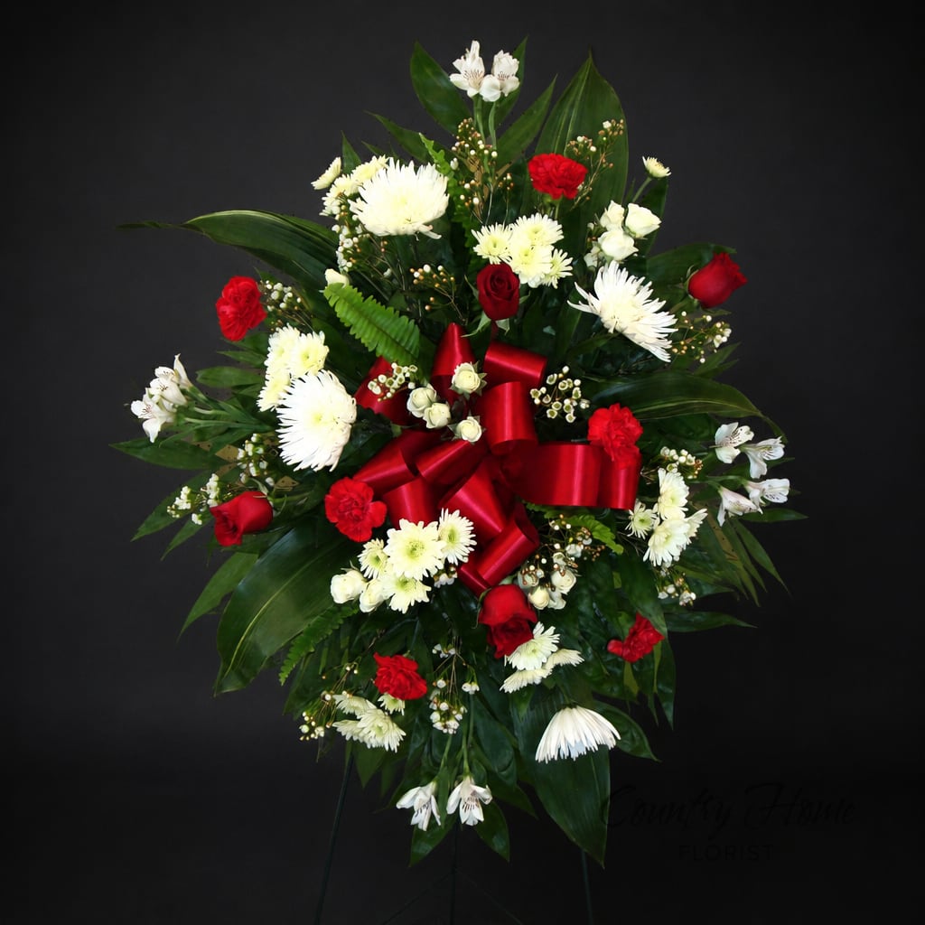 Red and white floral standing spray with a red ribbon bow