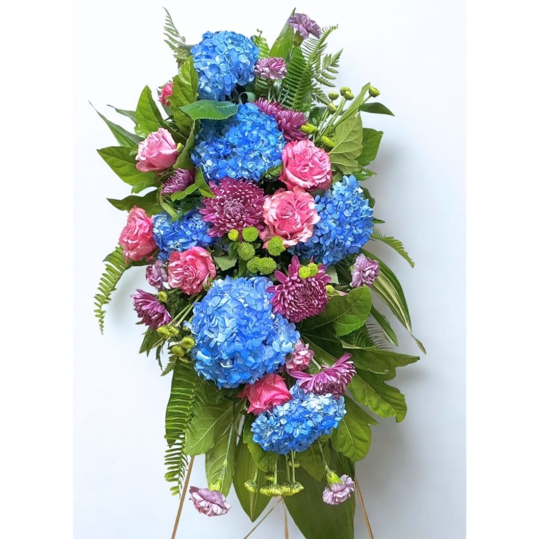Tall floral spray with blue hydrangeas, pink roses, and purple mums