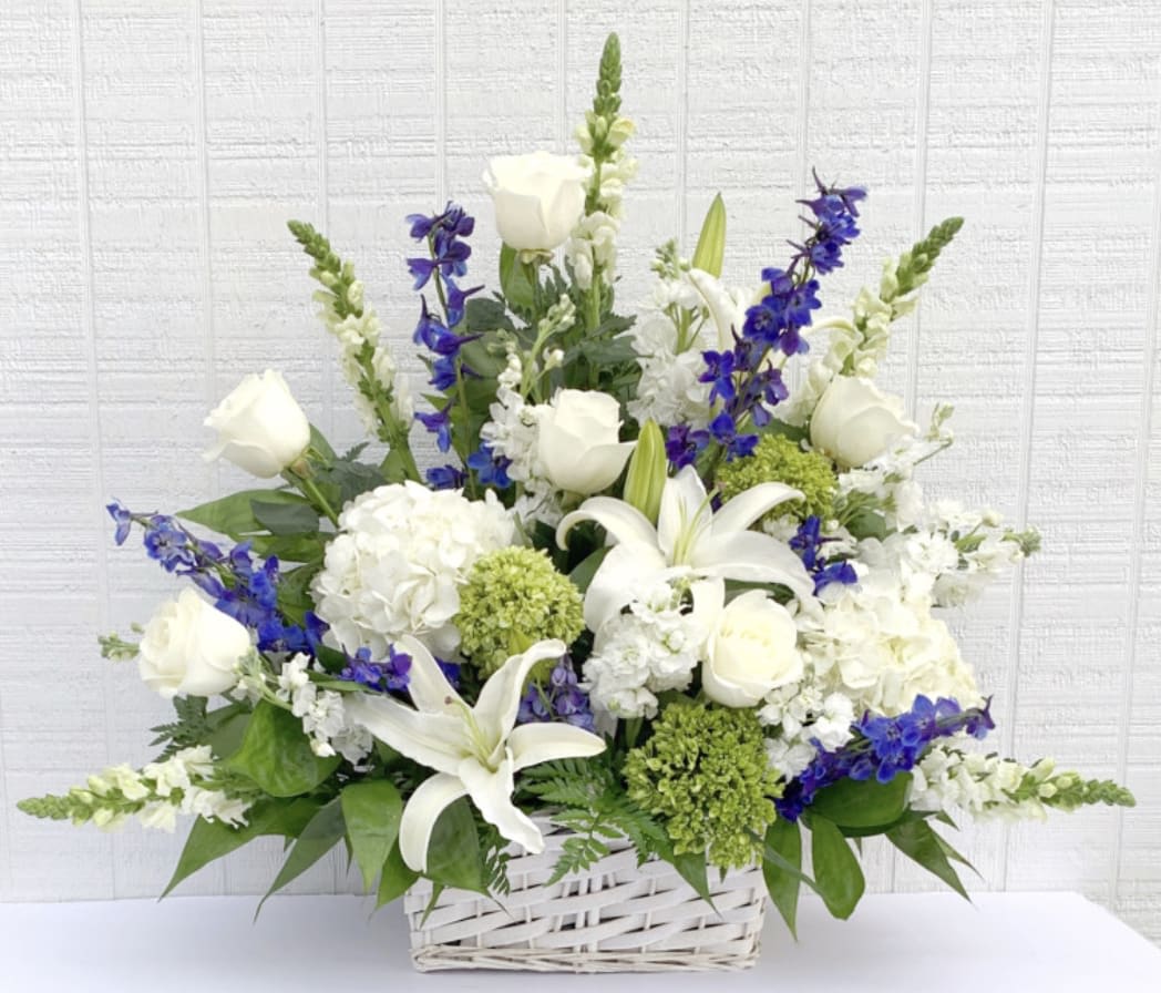 White lilies and roses with blue flowers in a white basket