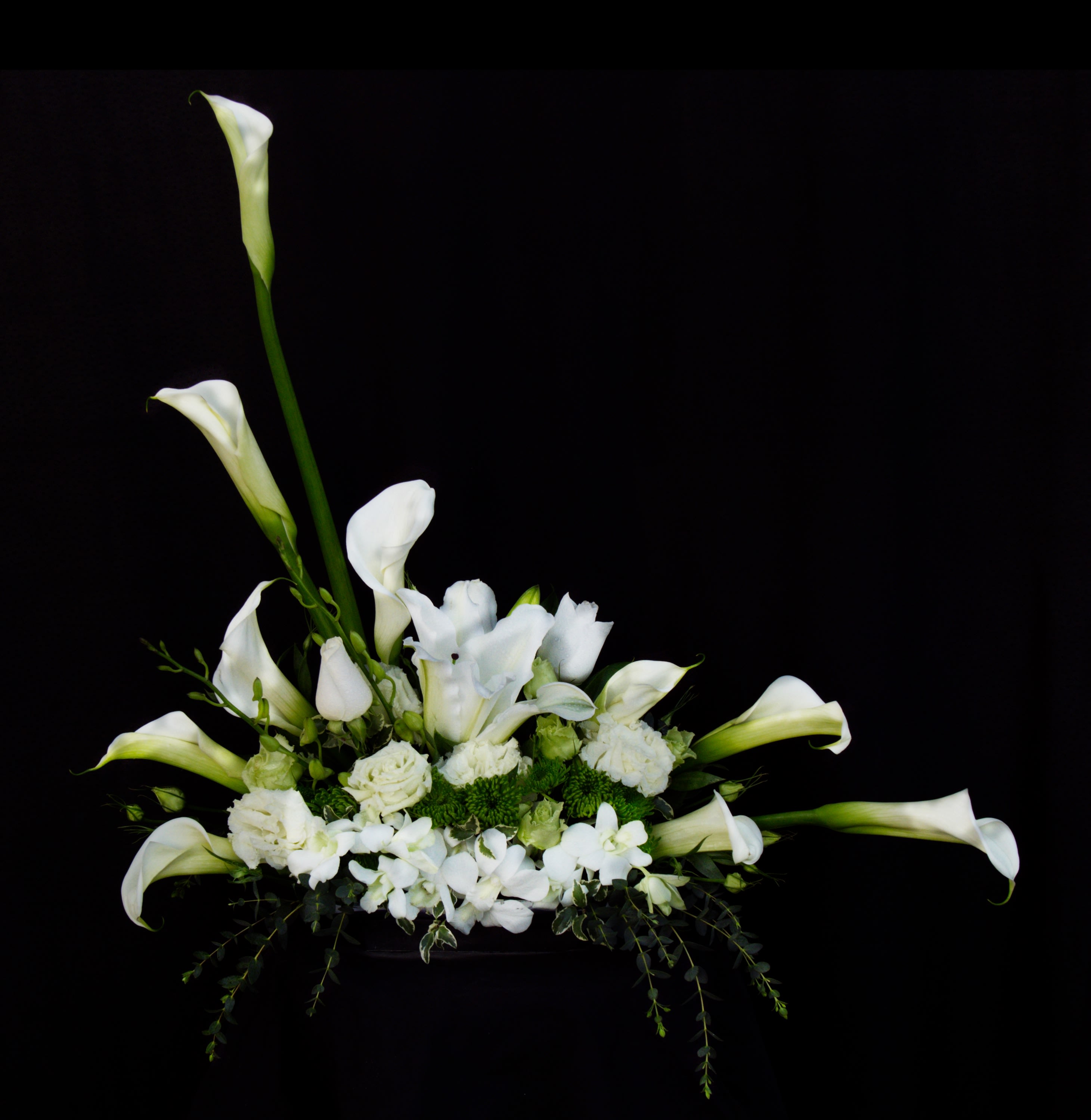 White calla lilies and orchids arranged in a low centerpiece
