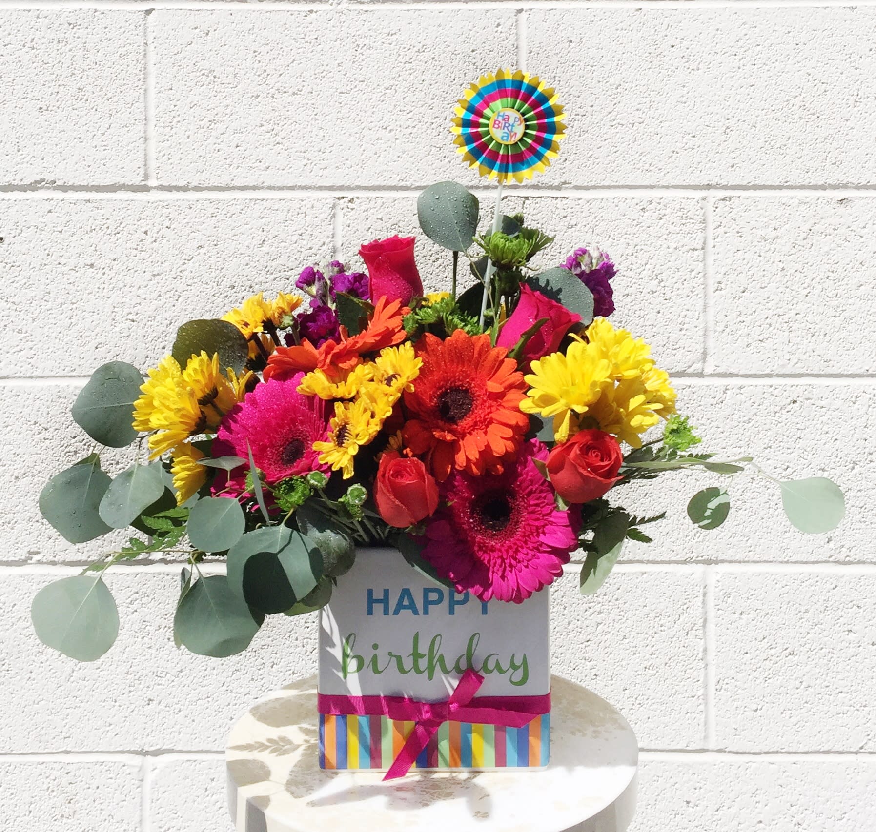 Birthday flower arrangement in a decorated gift box with a topper