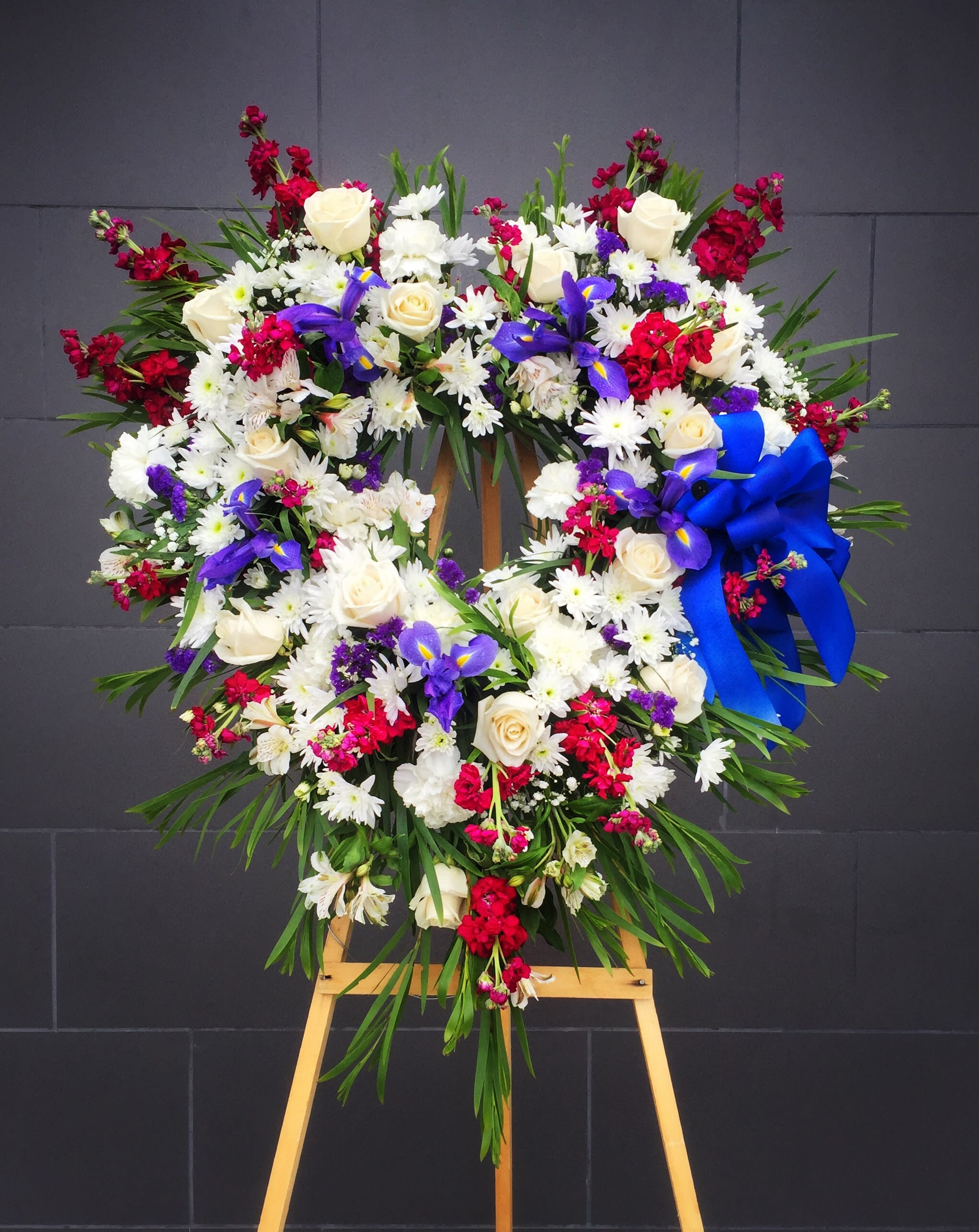 Large floral wreath on an easel with white, red, and purple flowers
