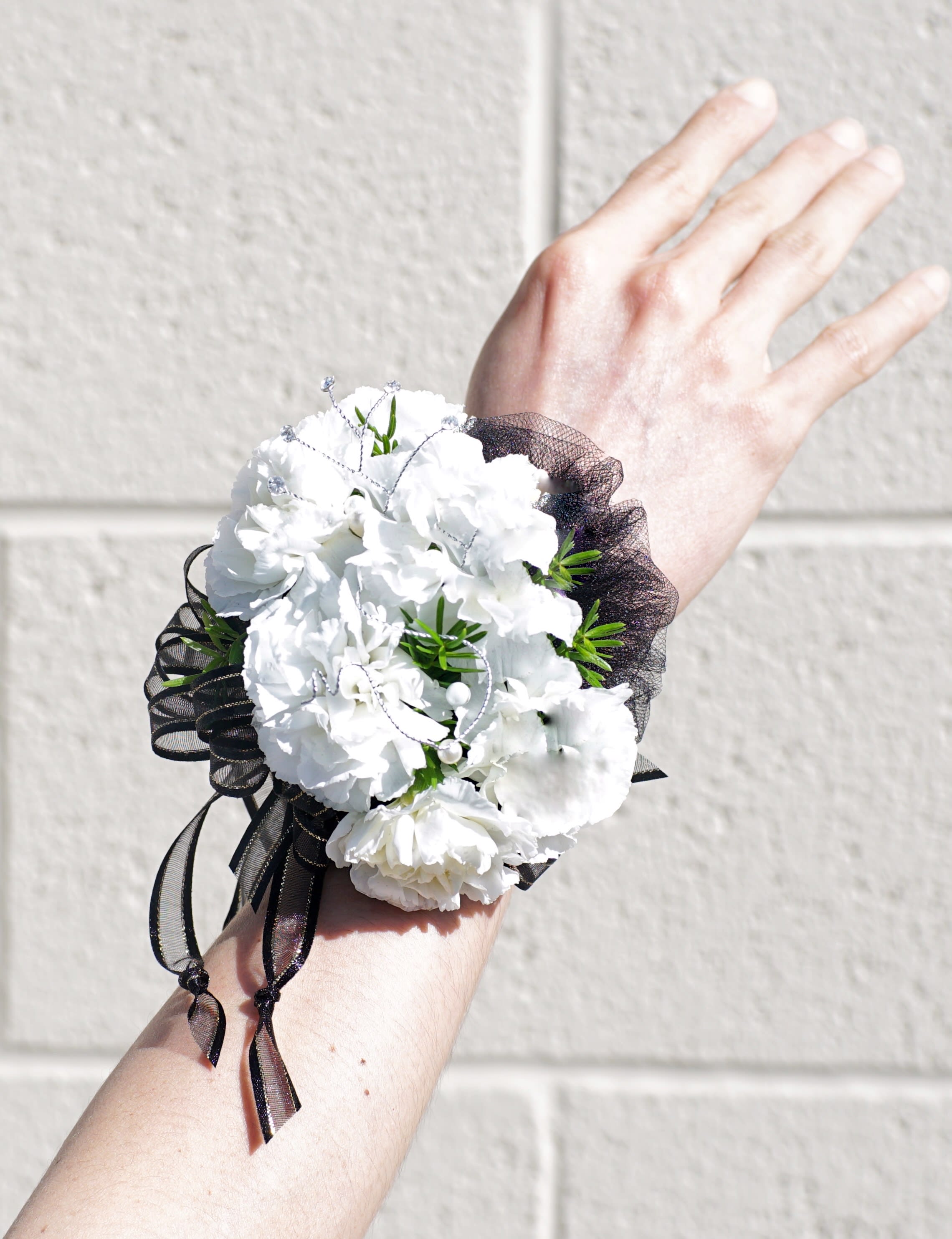White carnation wrist corsage with black ribbon