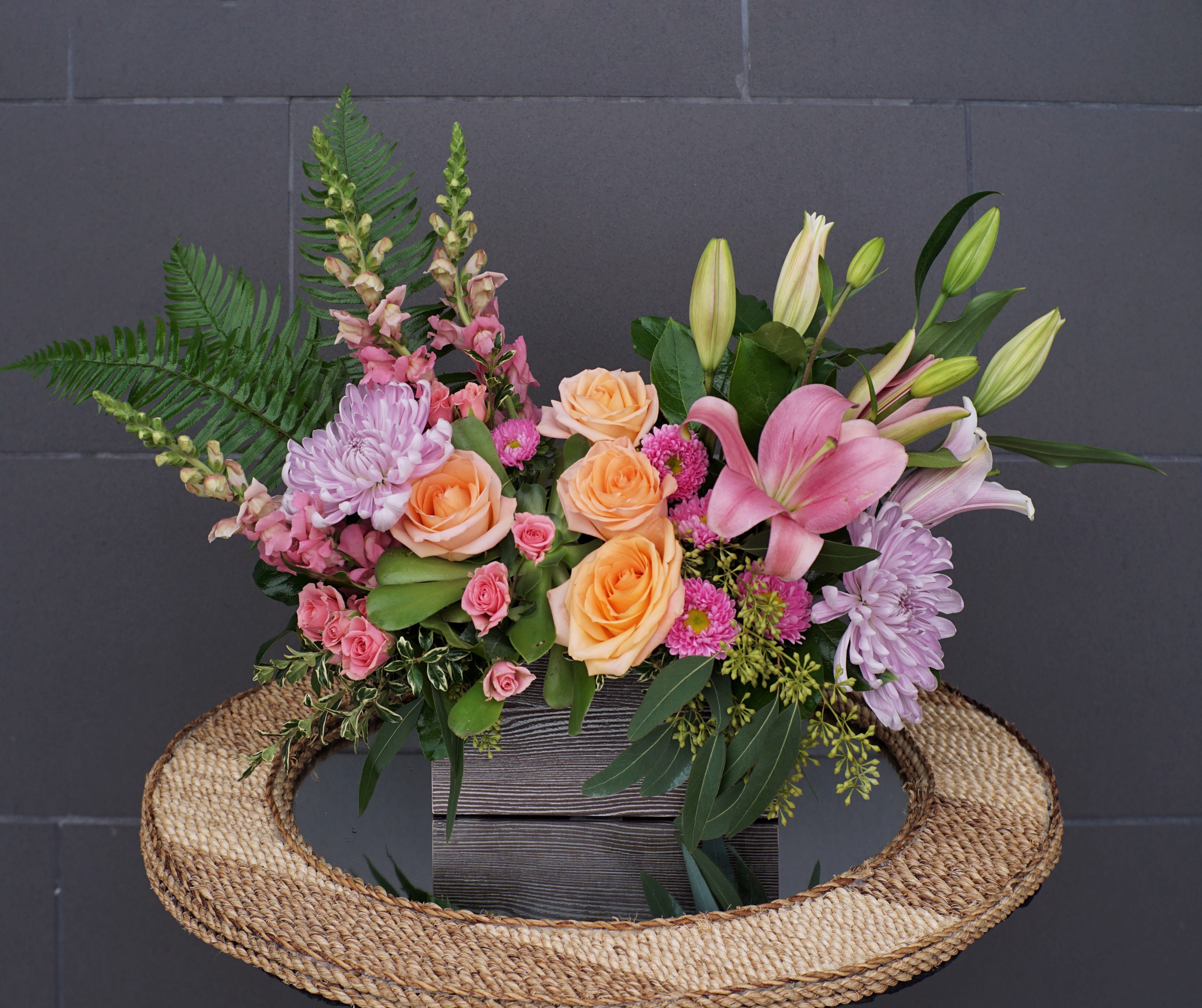 Mixed bouquet with peach roses, pink lilies, and lavender chrysanthemums in a wooden box