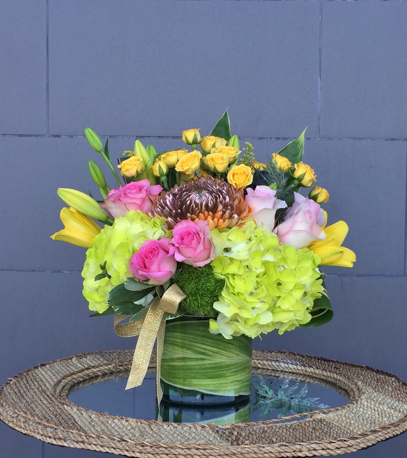 Bouquet of yellow and pink roses with lime hydrangeas in a green vase