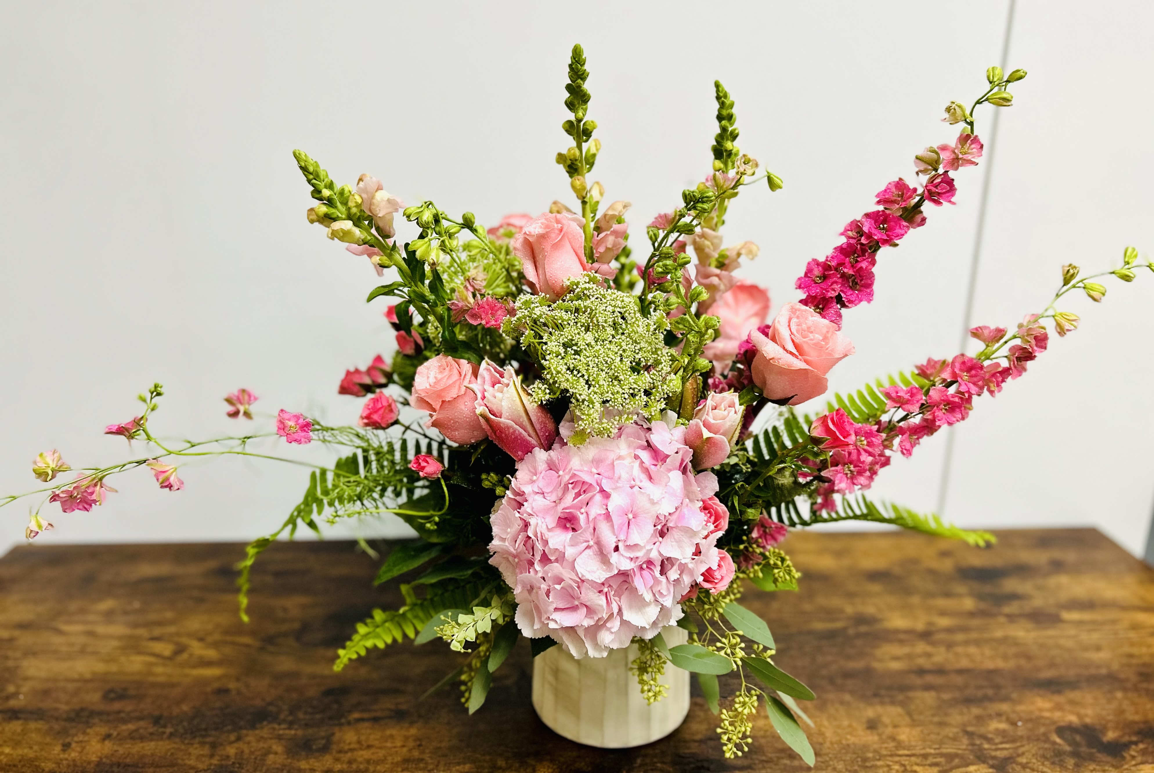 Pink floral arrangement in a white vase with tall spiky blooms