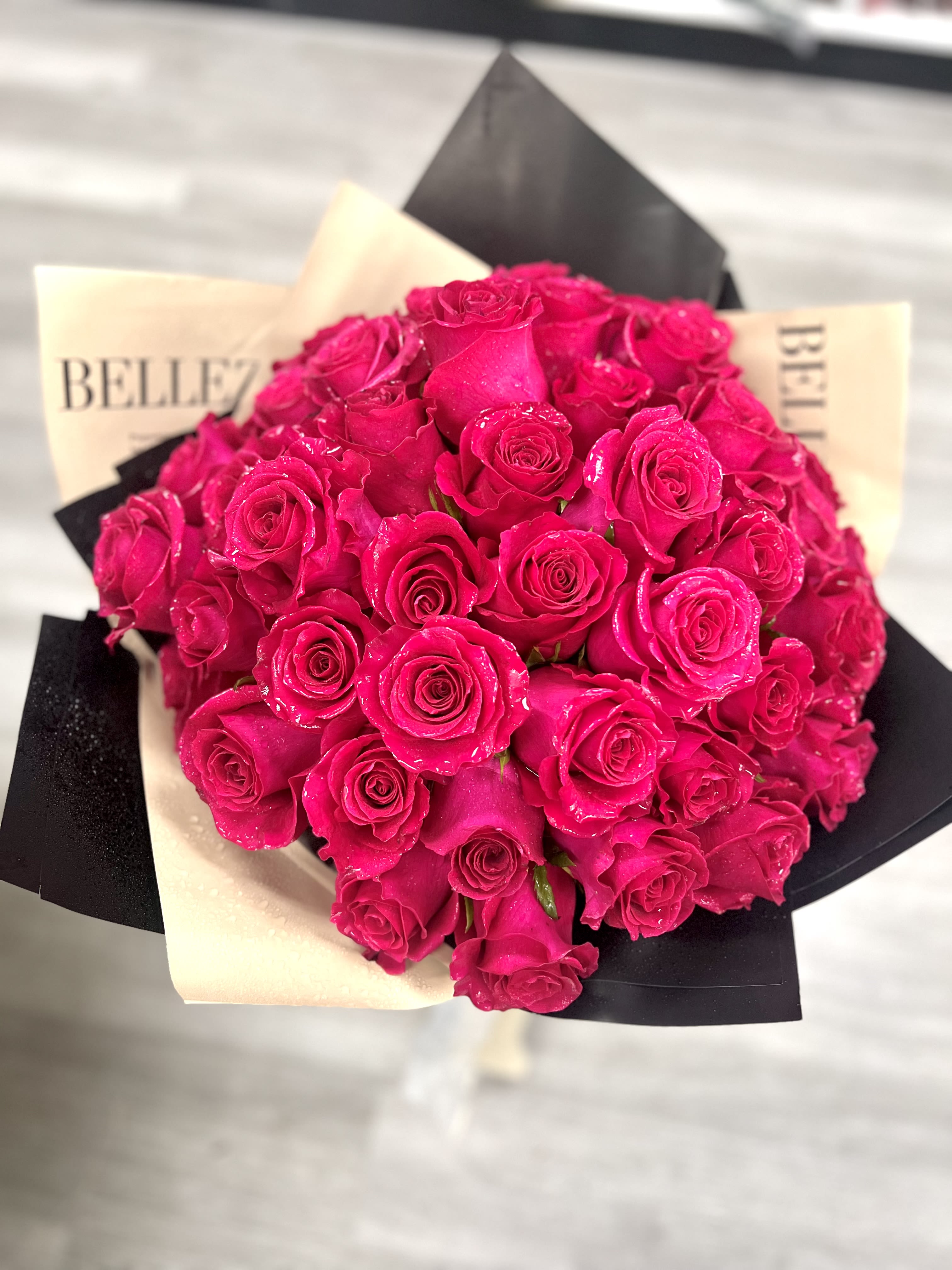 Bouquet of bright pink roses wrapped in black and cream paper