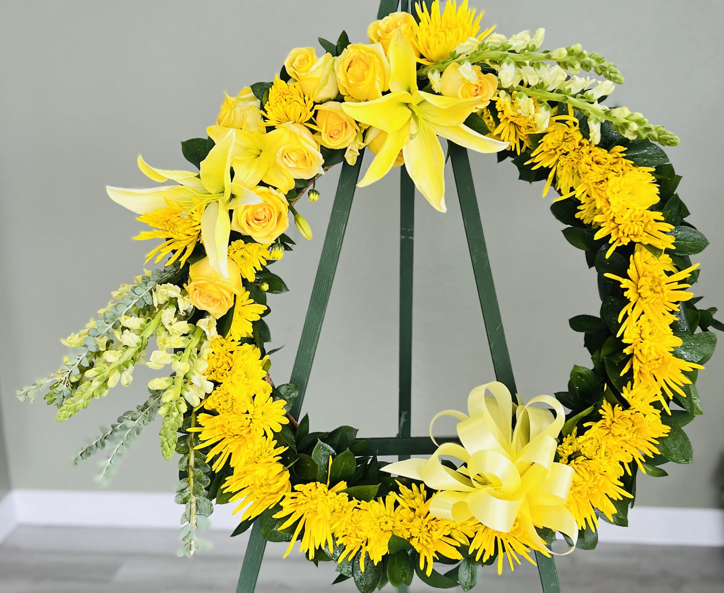Yellow floral wreath on a stand with roses and lilies