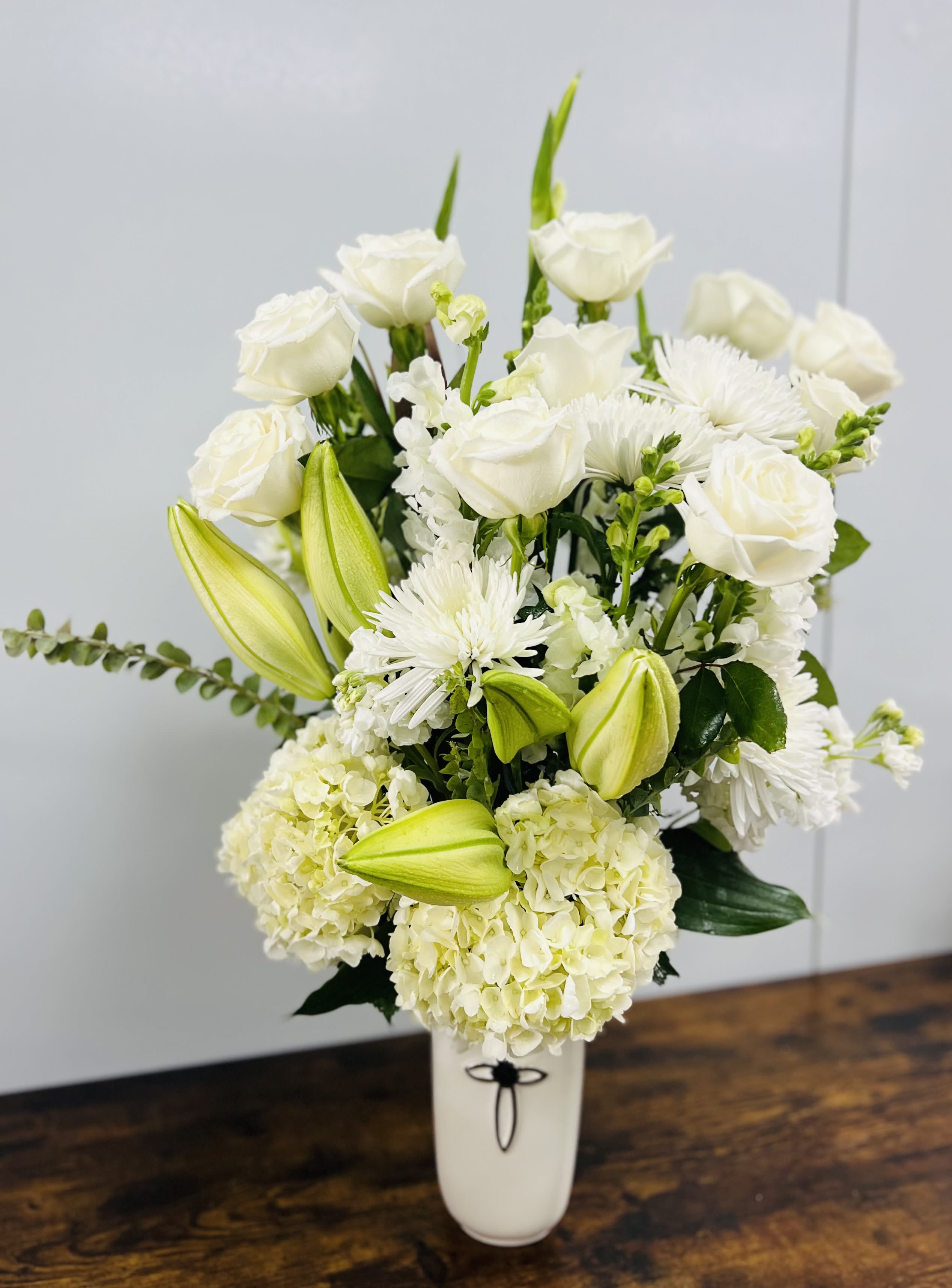 White floral arrangement with roses, lilies, and hydrangeas in a white vase