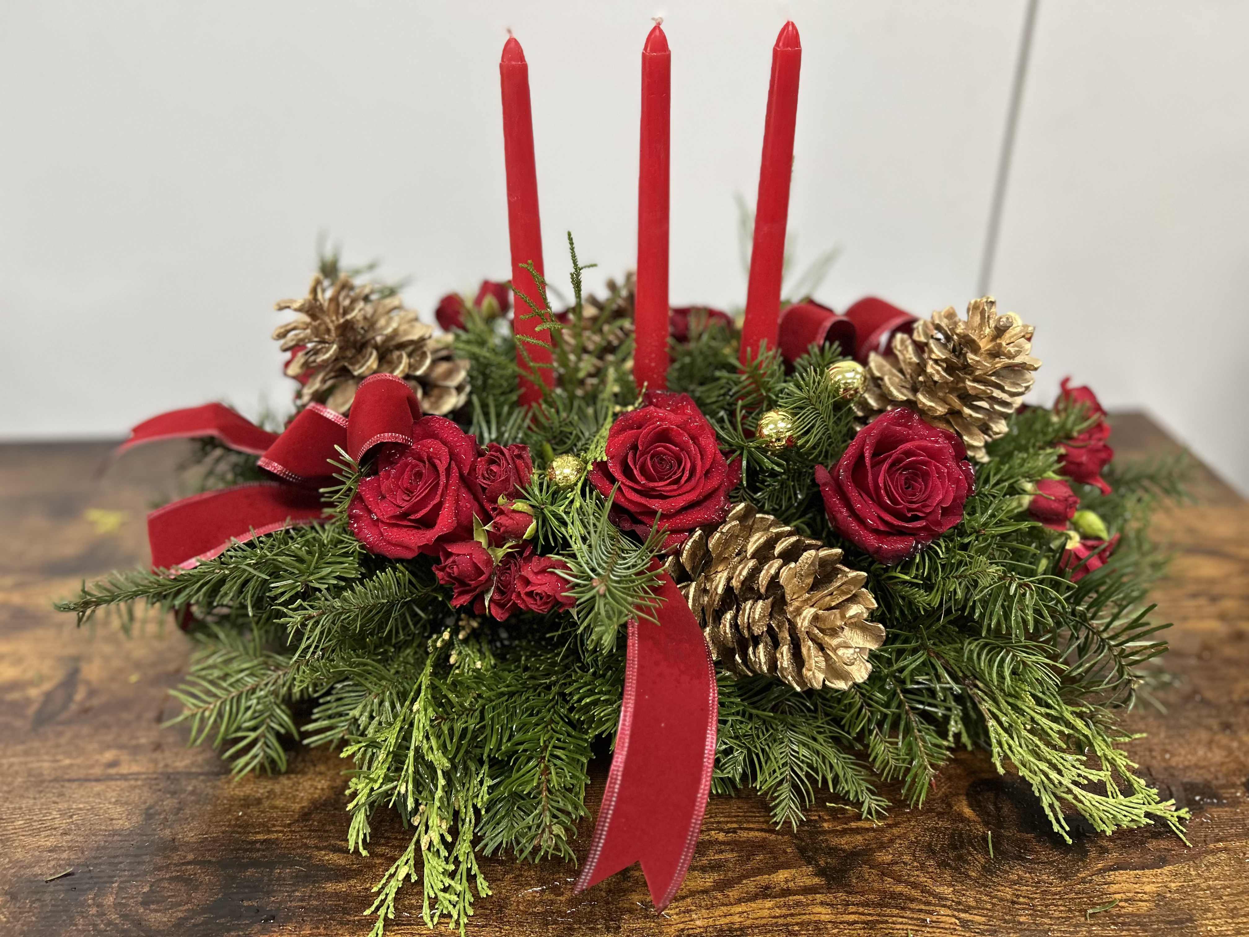 Holiday centerpiece with red candles, red roses, and gold pinecones
