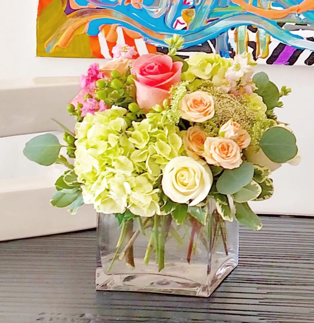 Bouquet of pink and peach roses with pale green hydrangeas in a clear glass vase