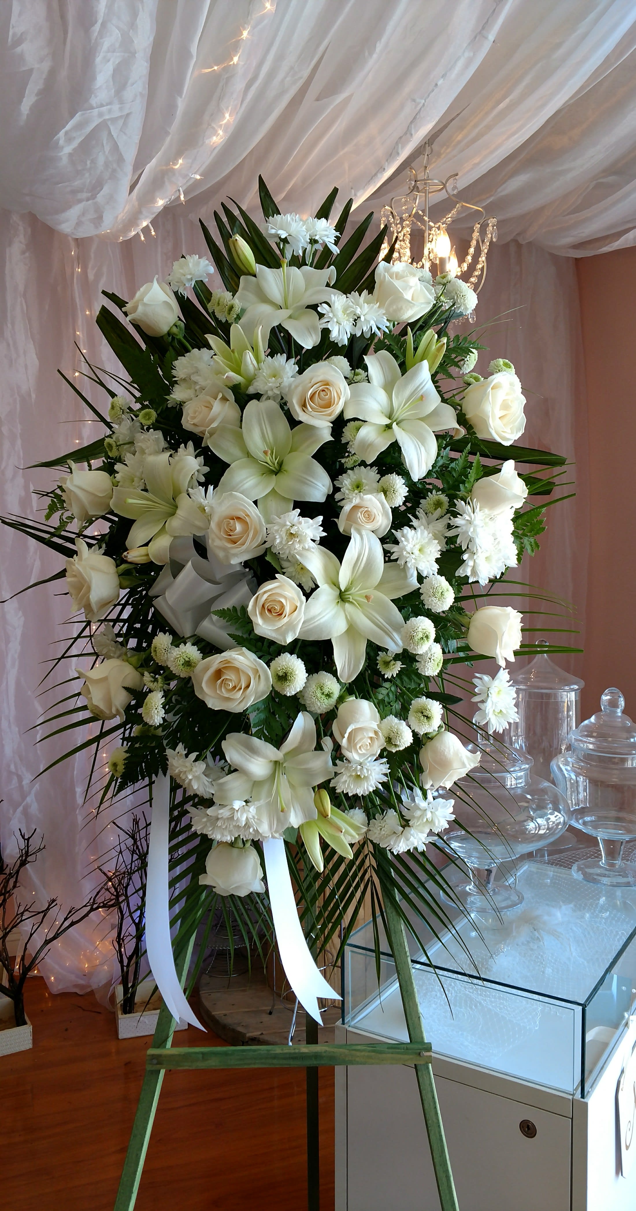 Large white floral standing spray on an easel with ribbon
