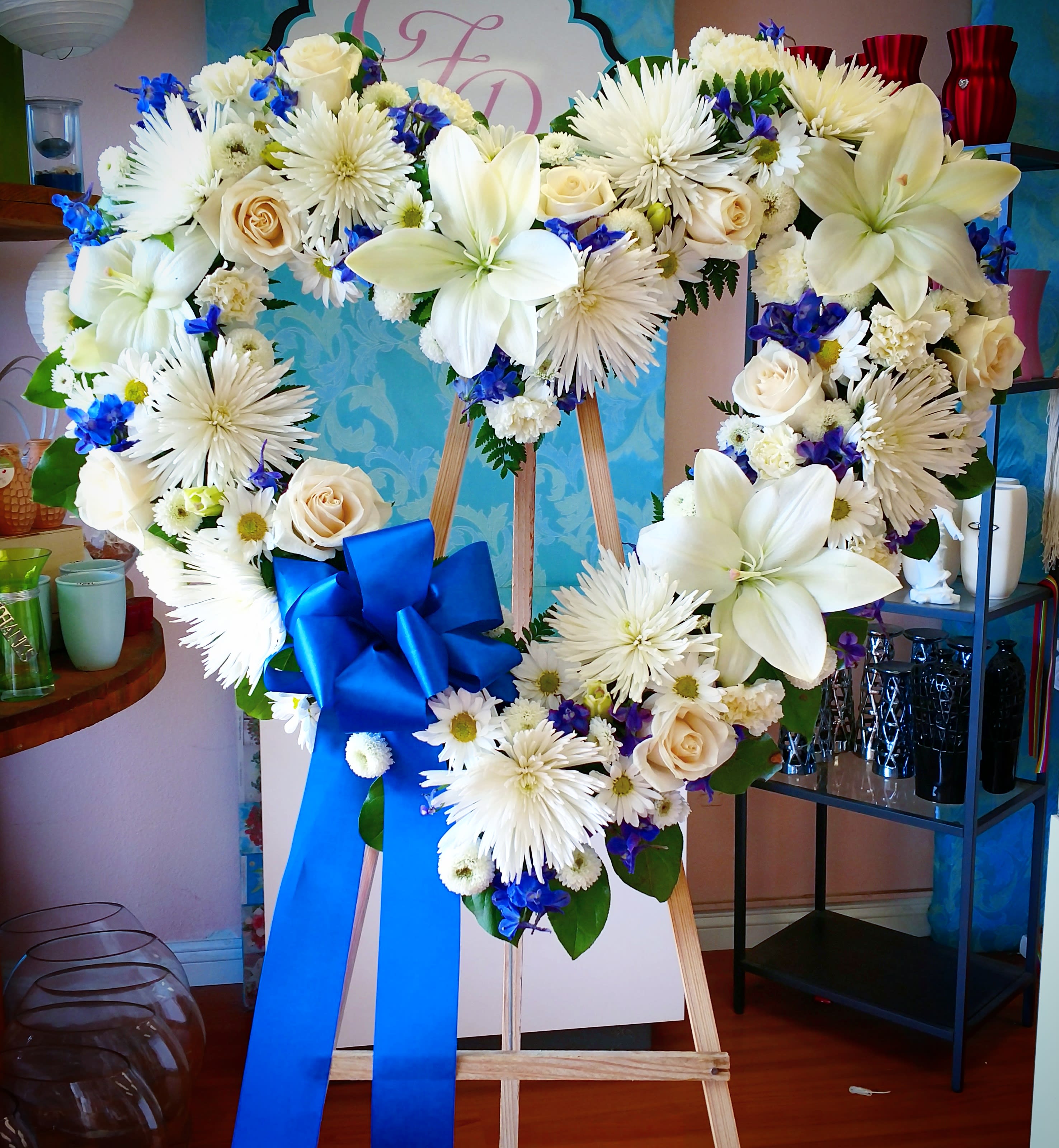 Heart-shaped floral wreath on an easel with a blue ribbon