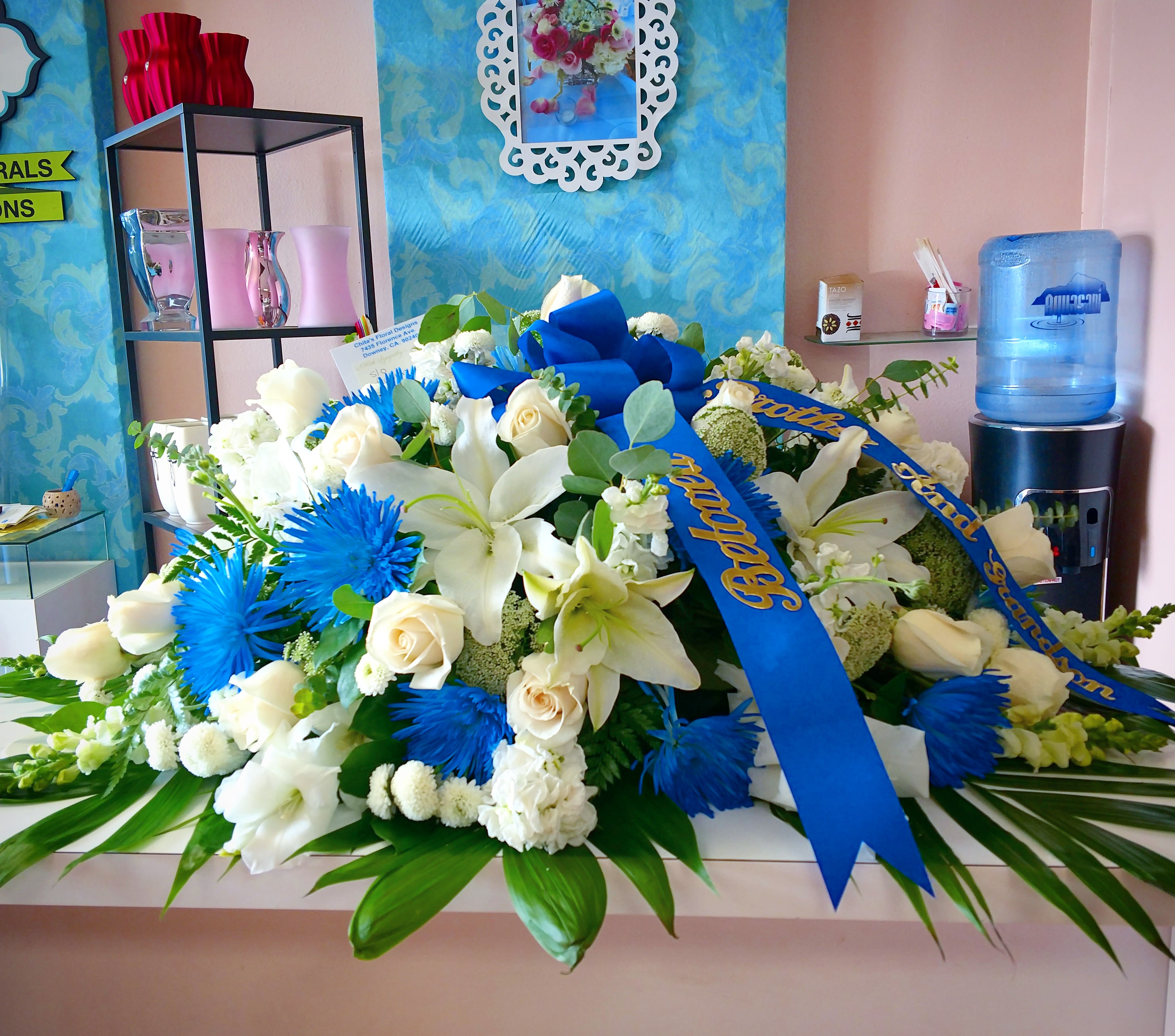 Large white and blue floral arrangement with ribbon on a table