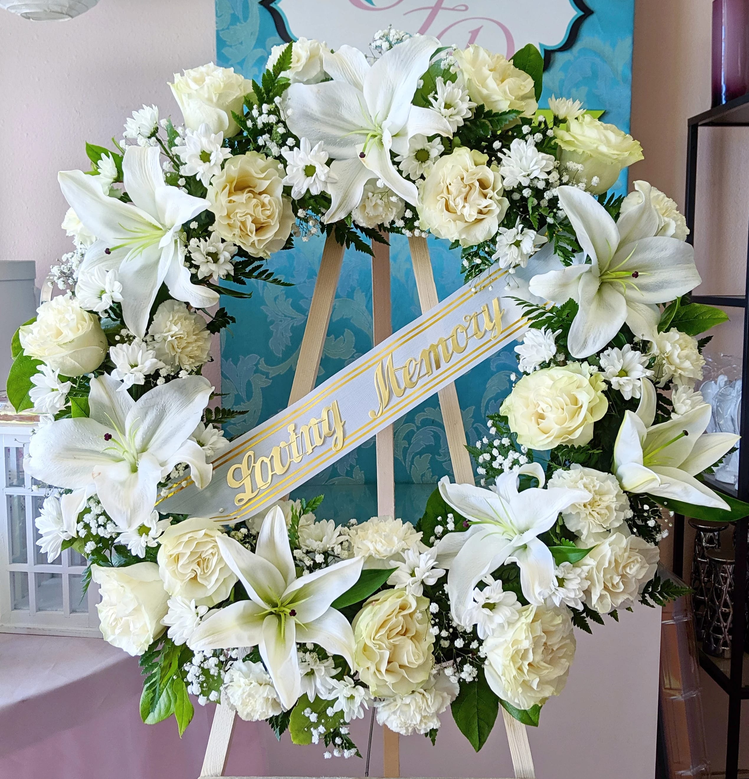 White floral wreath on an easel with a "Loving Memory" ribbon