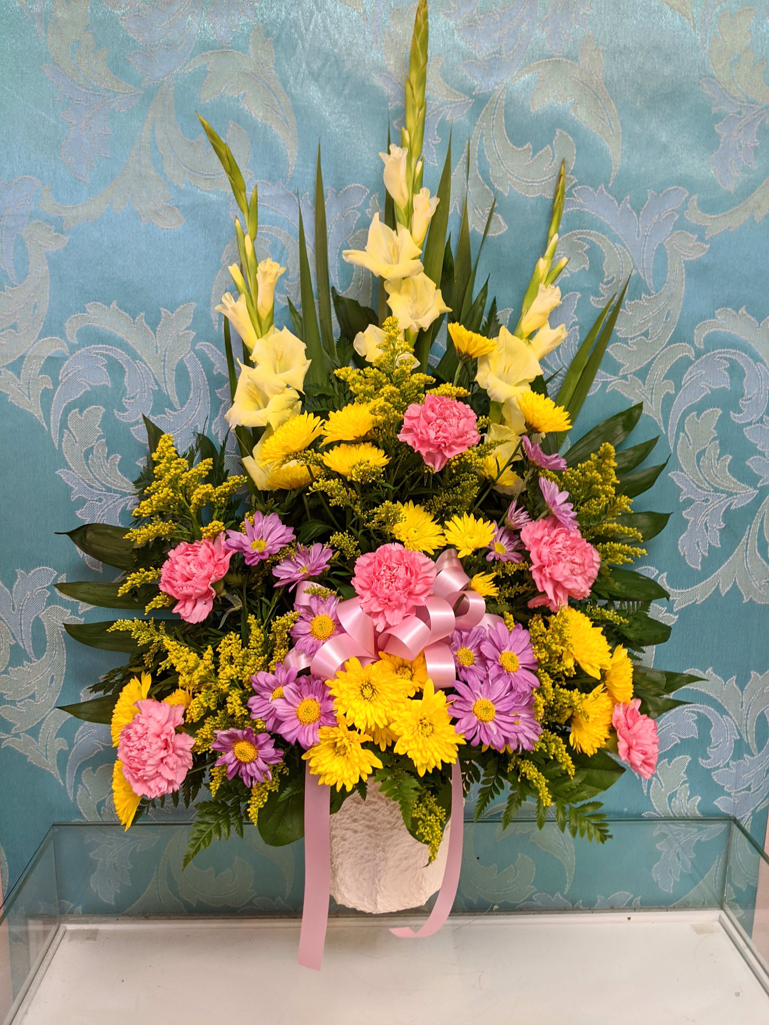 Tall floral arrangement with yellow, pink, and purple blooms in a white vase