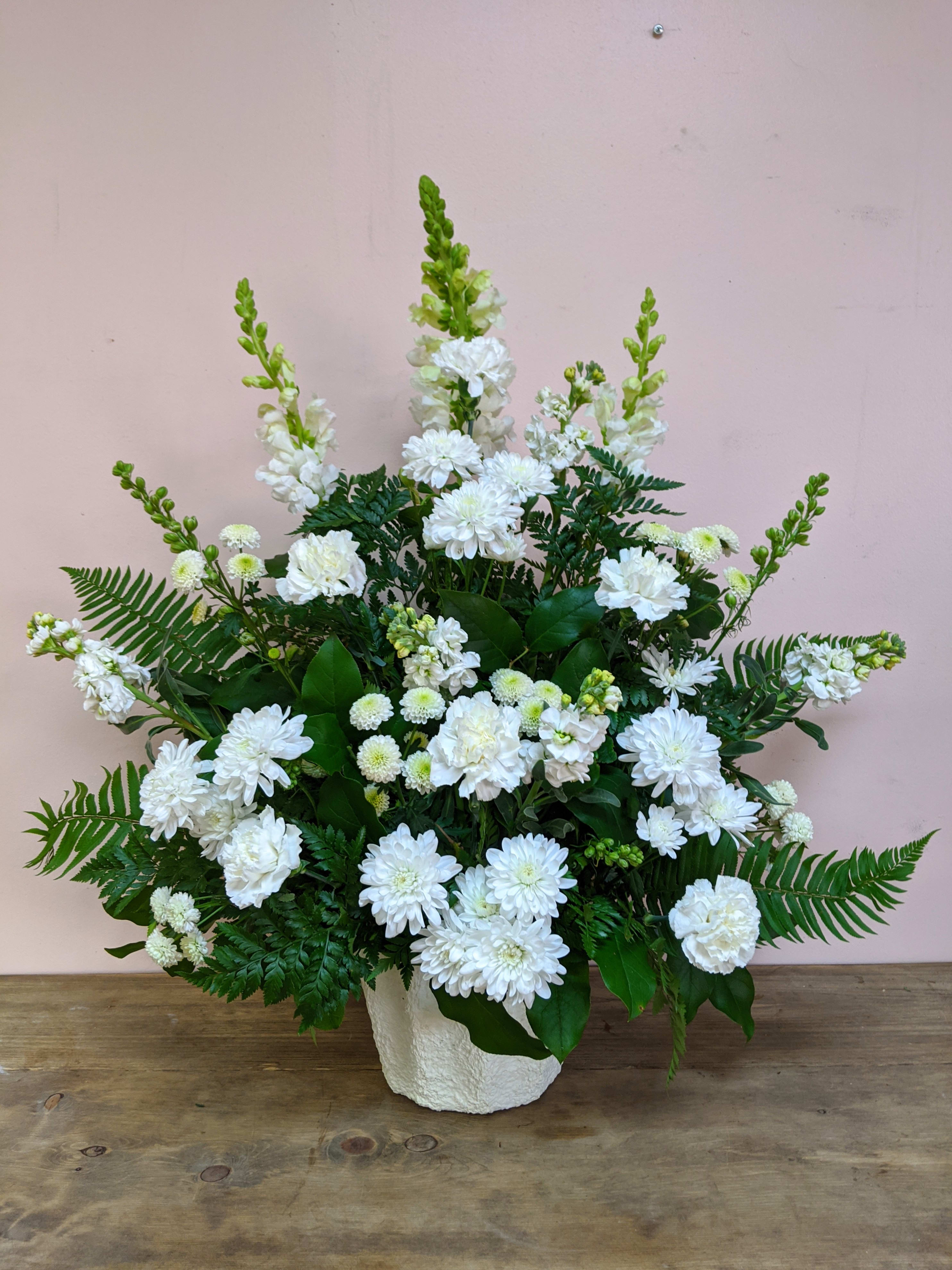 White floral arrangement in a textured white vase with fern accents