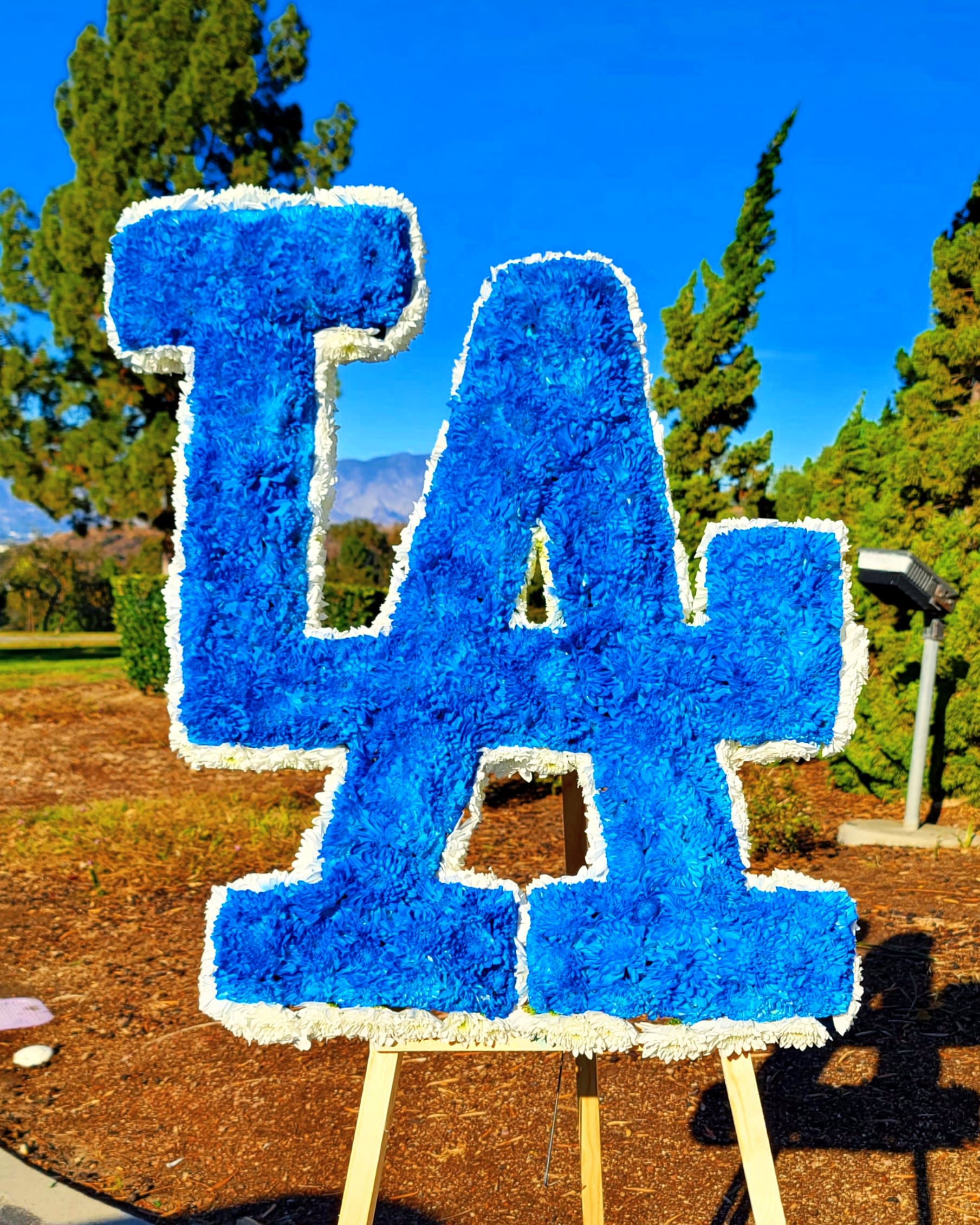 Large blue floral "LA" sign on an easel outdoors