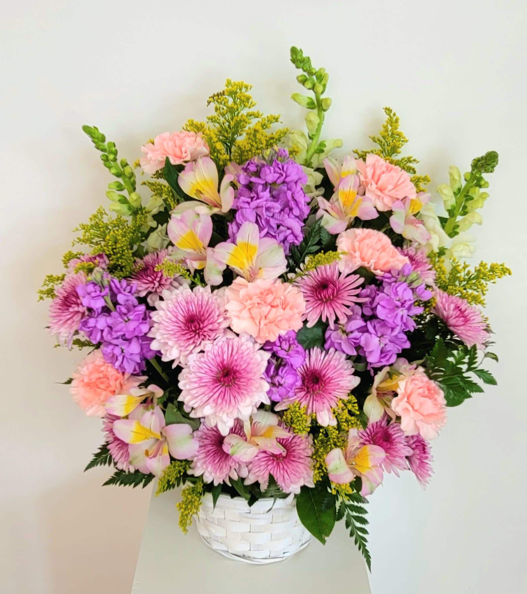 Pink and purple mixed flowers arranged in a white basket vase