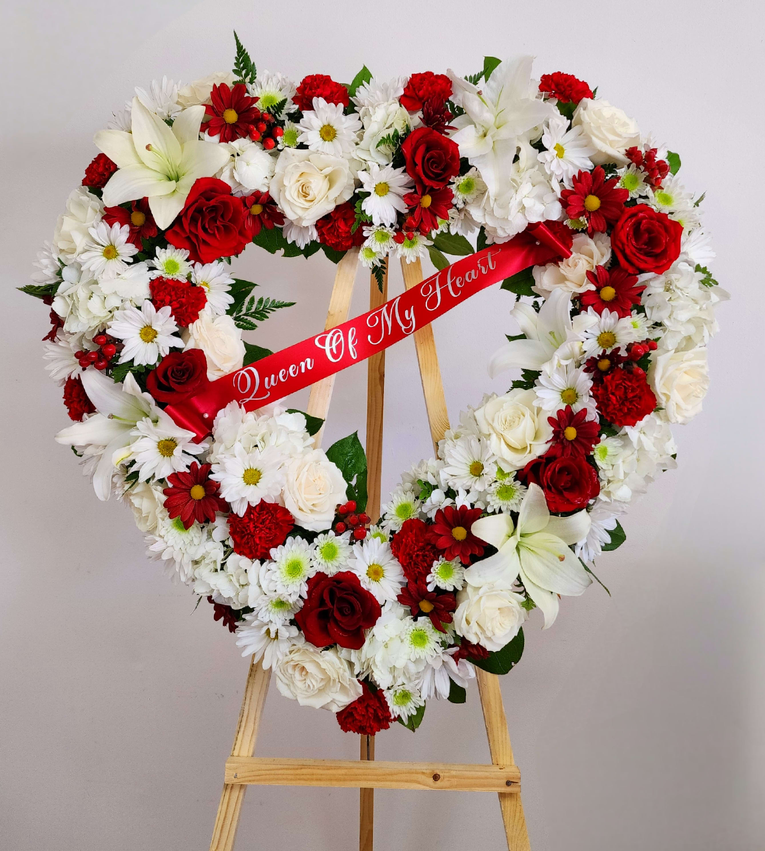 Heart-shaped floral wreath on an easel with a red ribbon