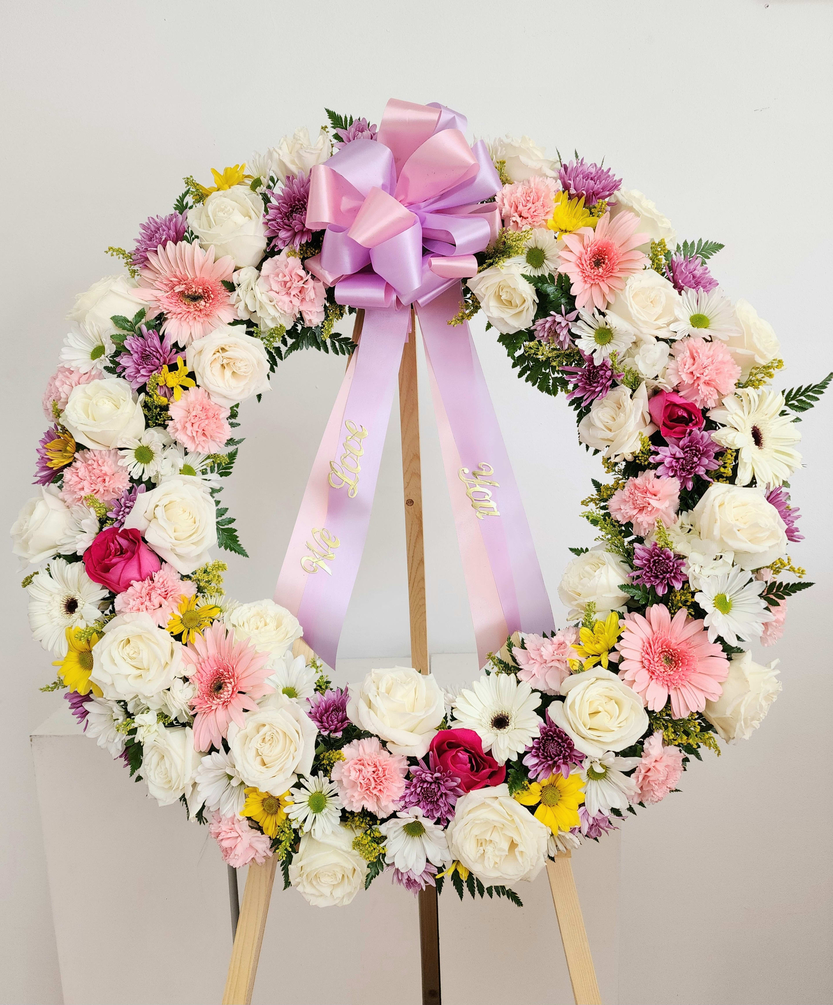 Floral wreath with pink ribbon on a wooden stand