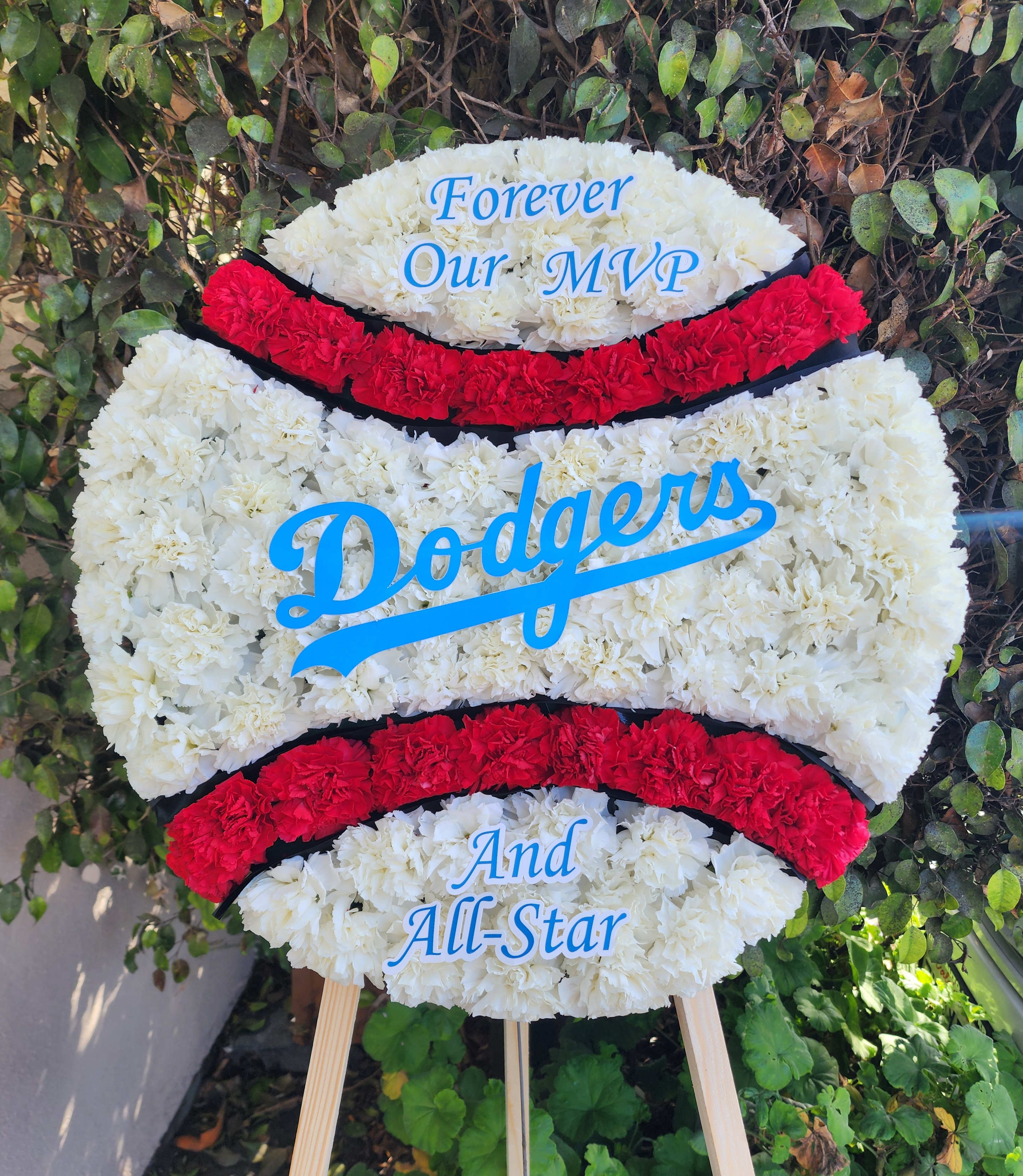 Dodgers-themed floral tribute on an easel with white and red flowers