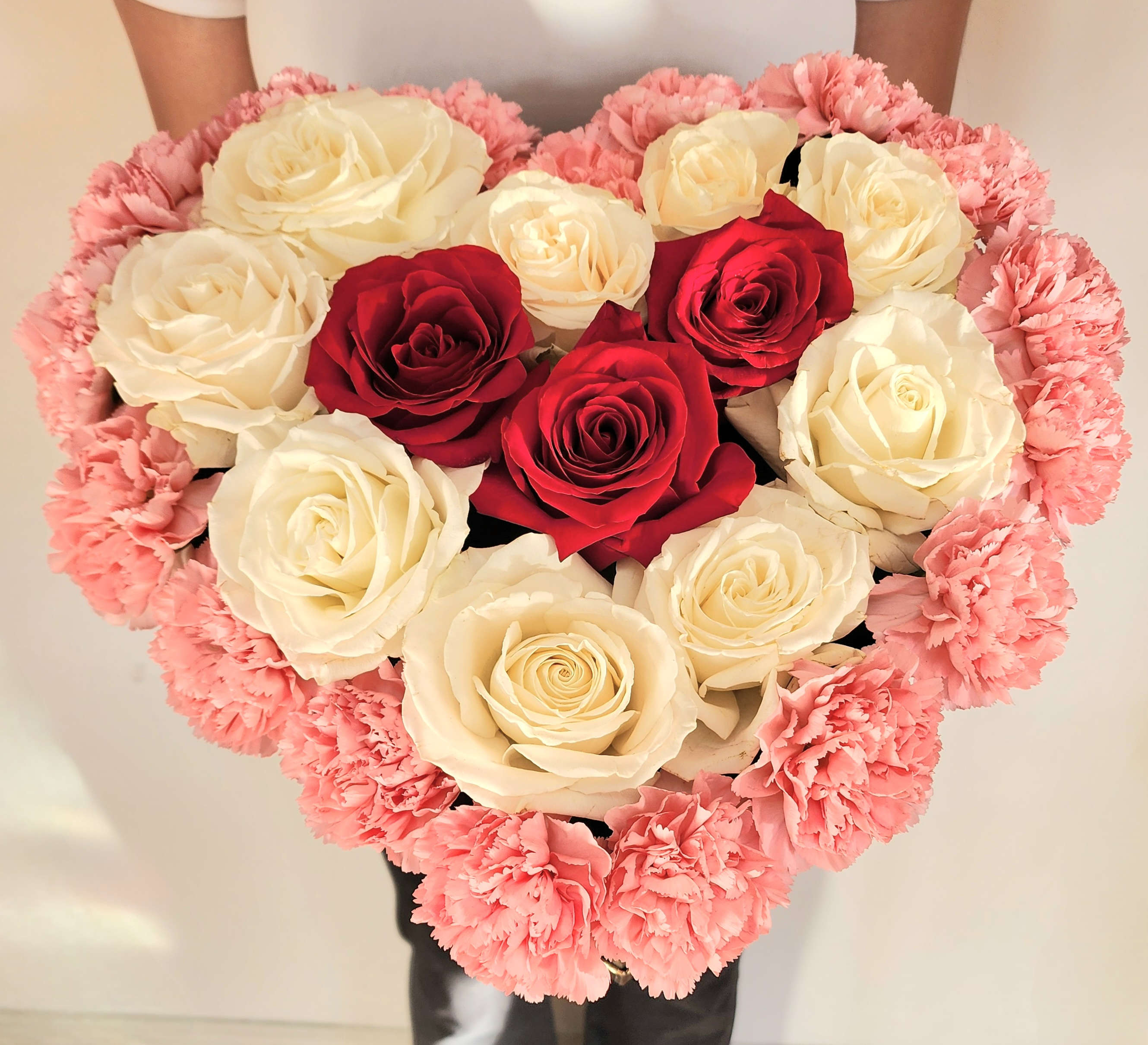 Heart-shaped bouquet of red and white roses edged with pink carnations