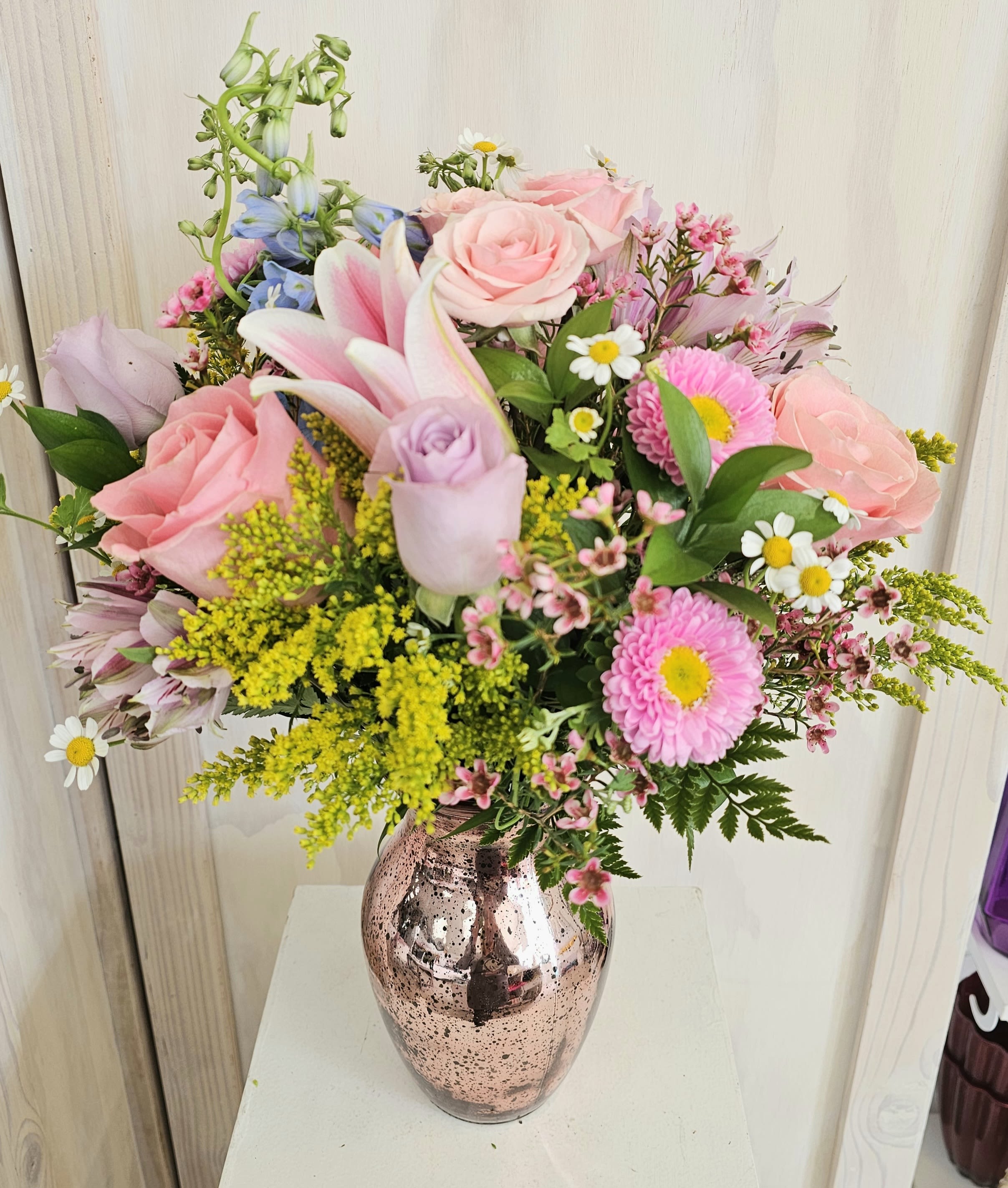 Mixed pink and pastel flowers arranged in a metallic vase