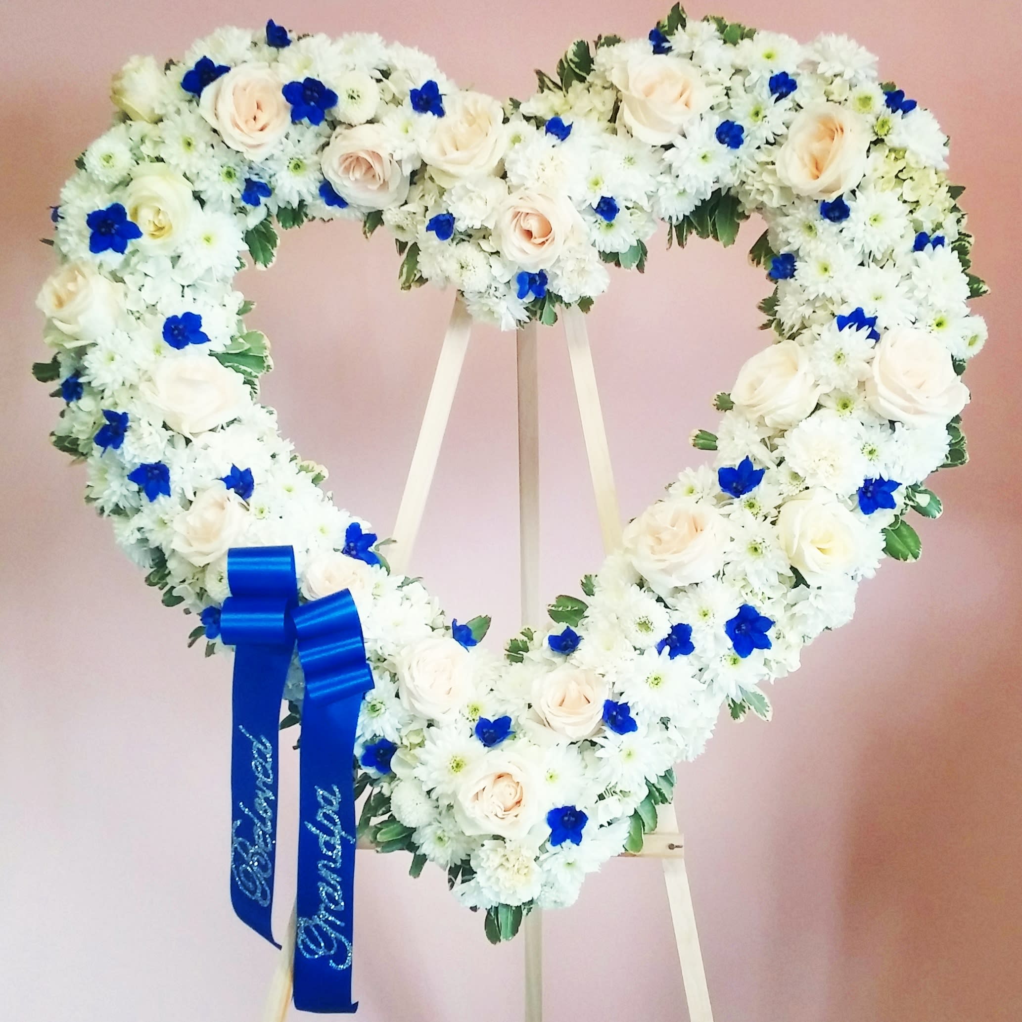Heart-shaped floral wreath of white and blue flowers on an easel