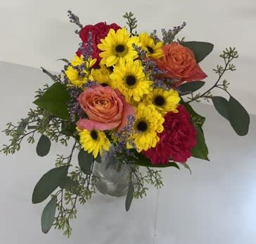Bouquet of yellow daisies and pink roses in a clear vase