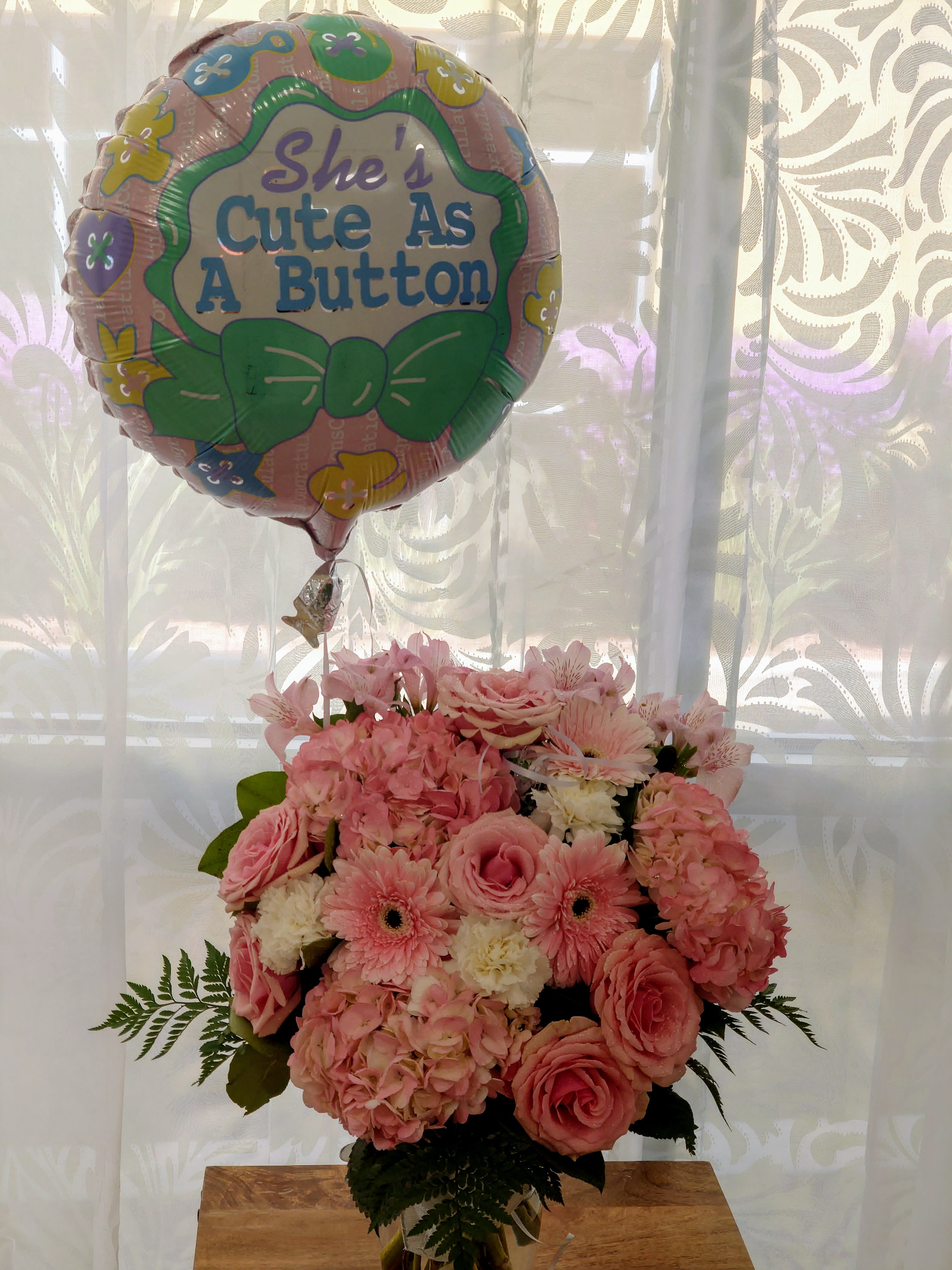 Pink flower bouquet with a "She's Cute As A Button" balloon