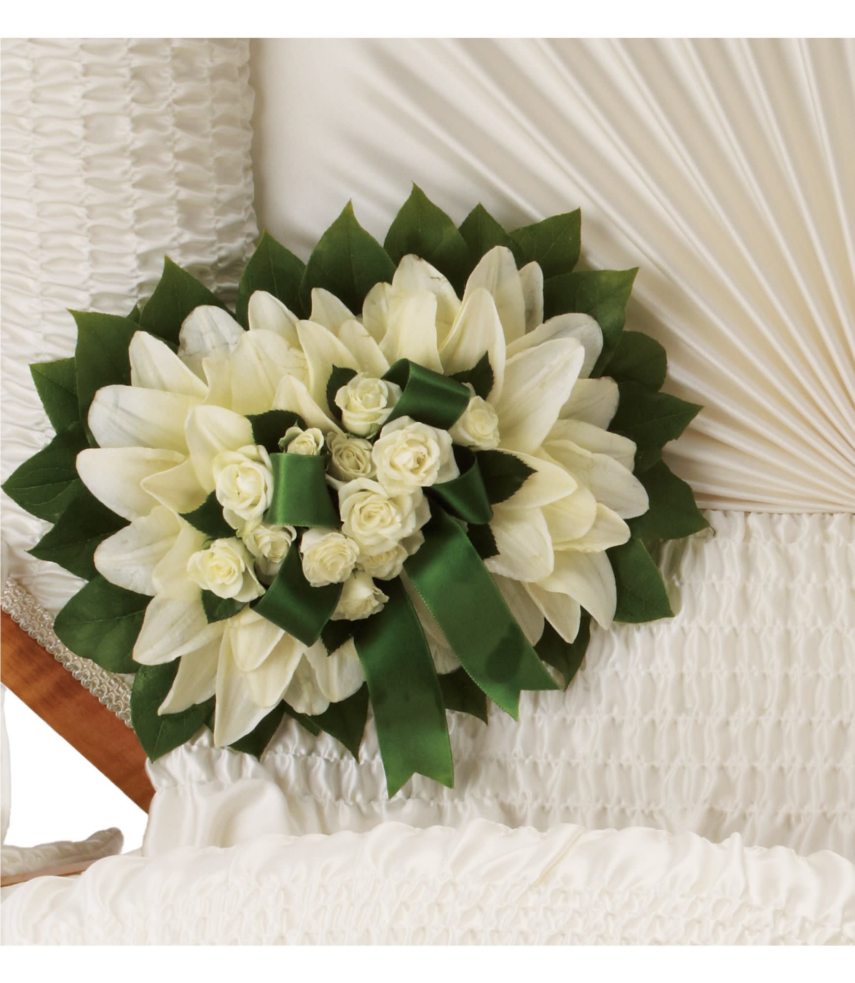 White lilies and roses with green ribbon arranged on a white casket interior