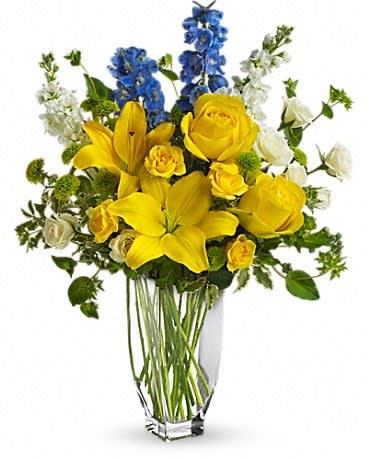 Yellow lilies and roses with blue and white flowers in a clear vase