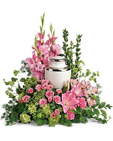Pink flowers arranged around a white urn with greenery