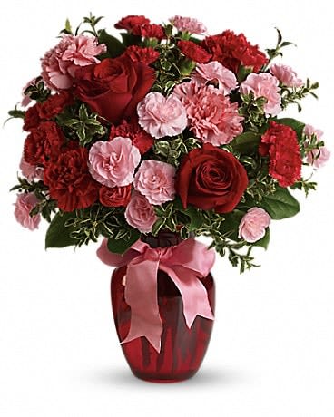 Red roses and pink carnations in a red vase with a pink ribbon