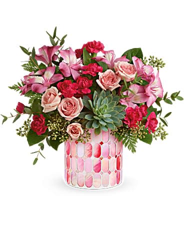 Pink and red floral arrangement in a patterned glass vase