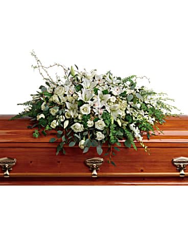 White floral casket spray on a wooden coffin