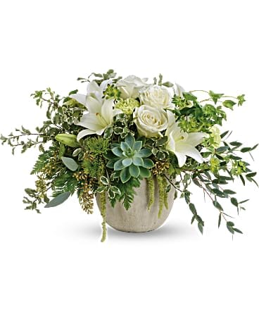 White lilies and roses in a low beige vase with trailing greenery