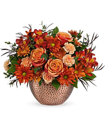 Orange and peach flower arrangement in a patterned vase