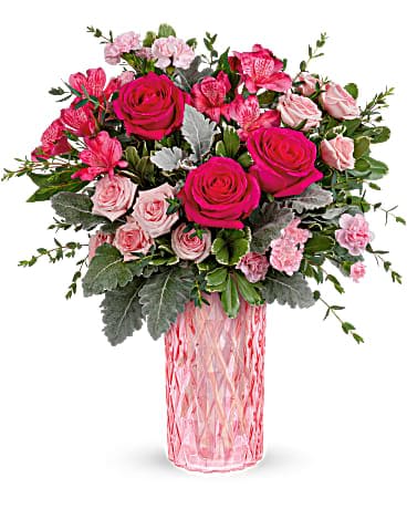 Pink roses and carnations arranged in a pink glass vase