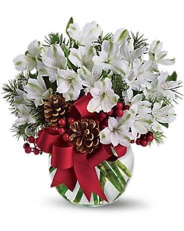 White flowers in a glass vase with pinecones and a red ribbon