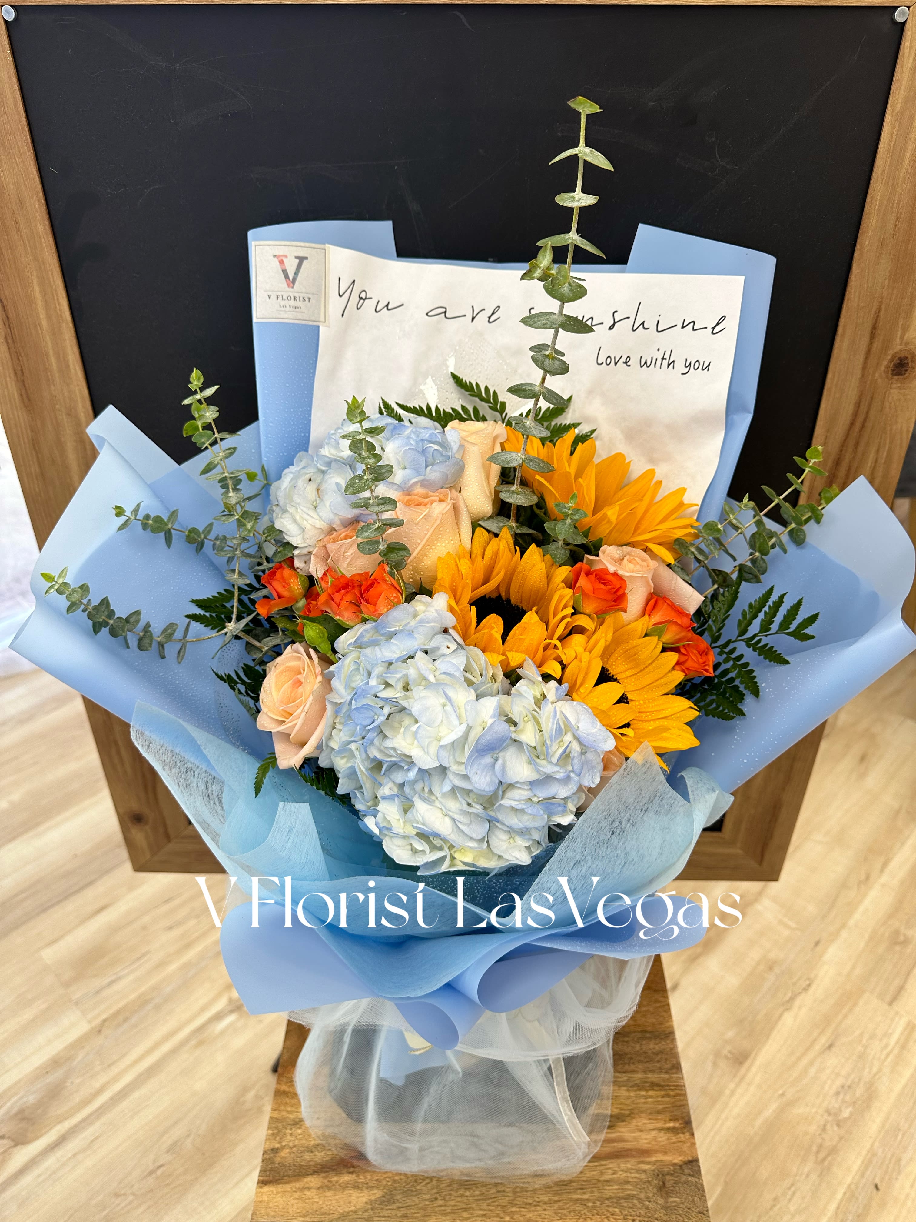 Blue and peach bouquet with hydrangeas, roses, and sunflowers