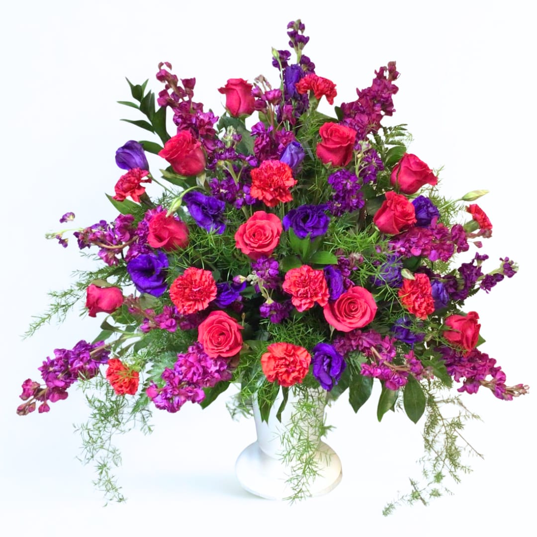 Pink and purple mixed flower arrangement in a white vase