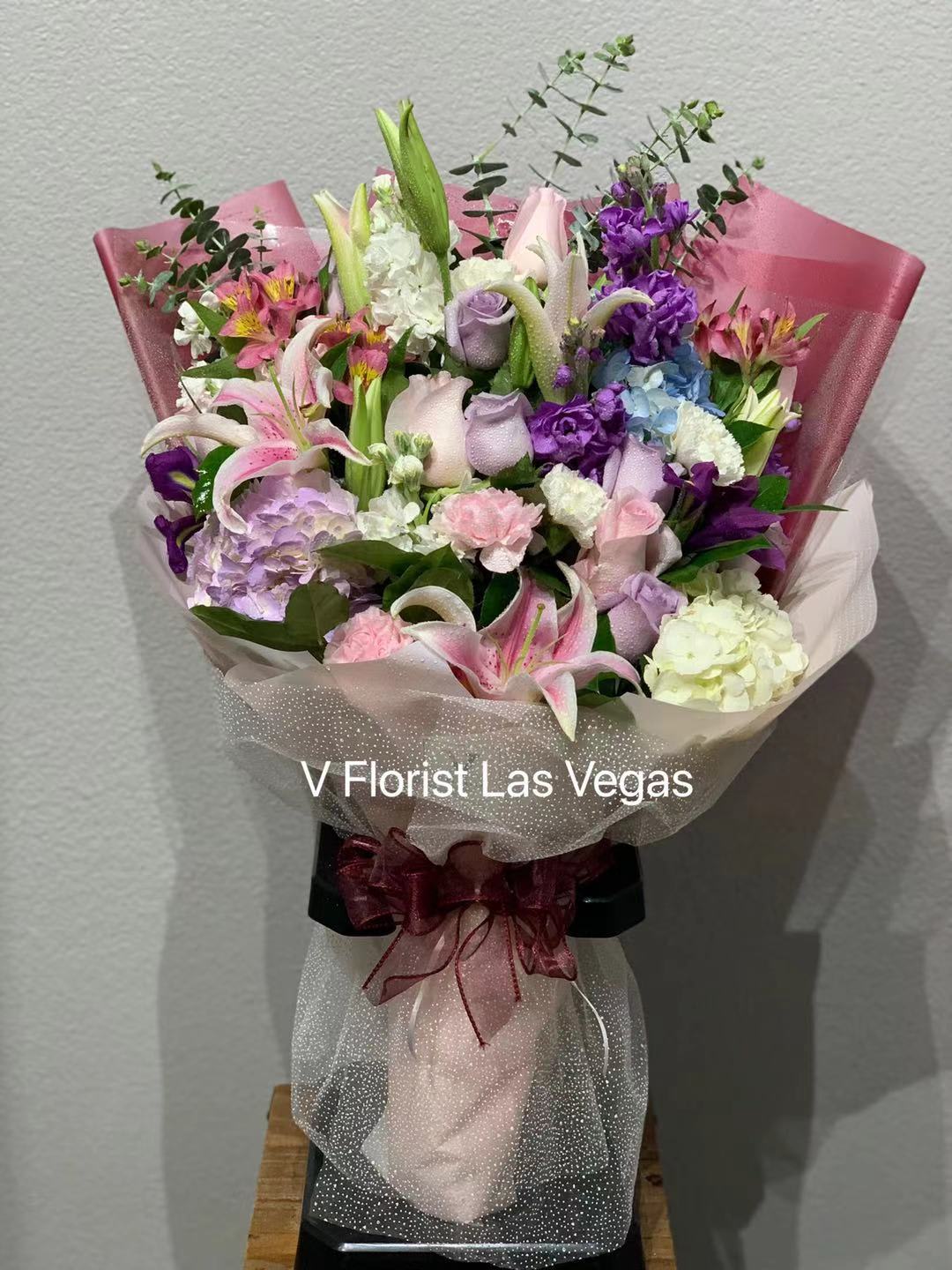 Bouquet of pink, purple, and white flowers wrapped in pink paper