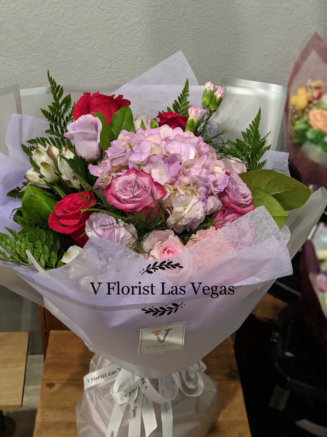 Bouquet of pink and red roses with hydrangea in lavender wrap