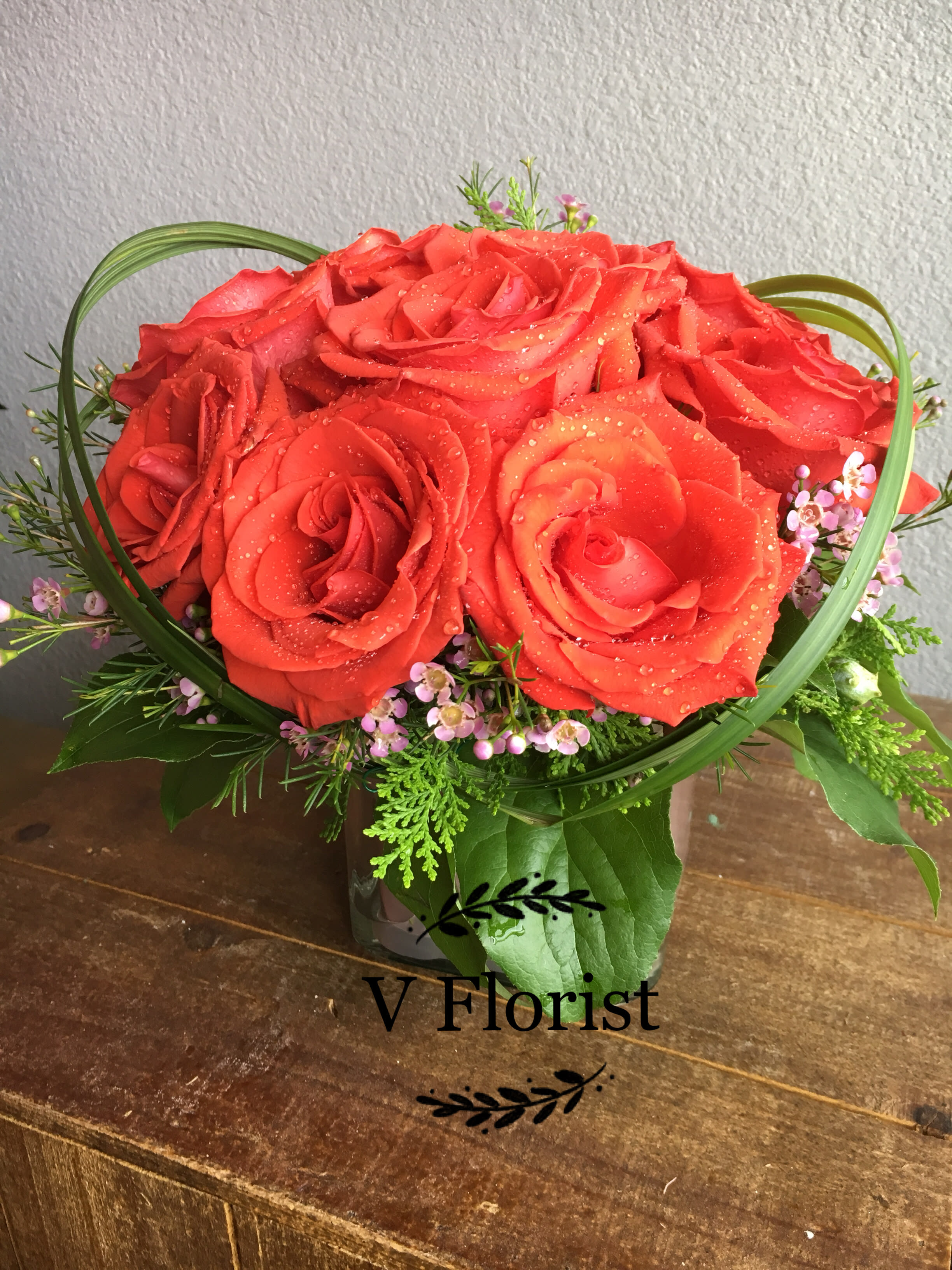 Red rose bouquet with small pink filler flowers in a vase