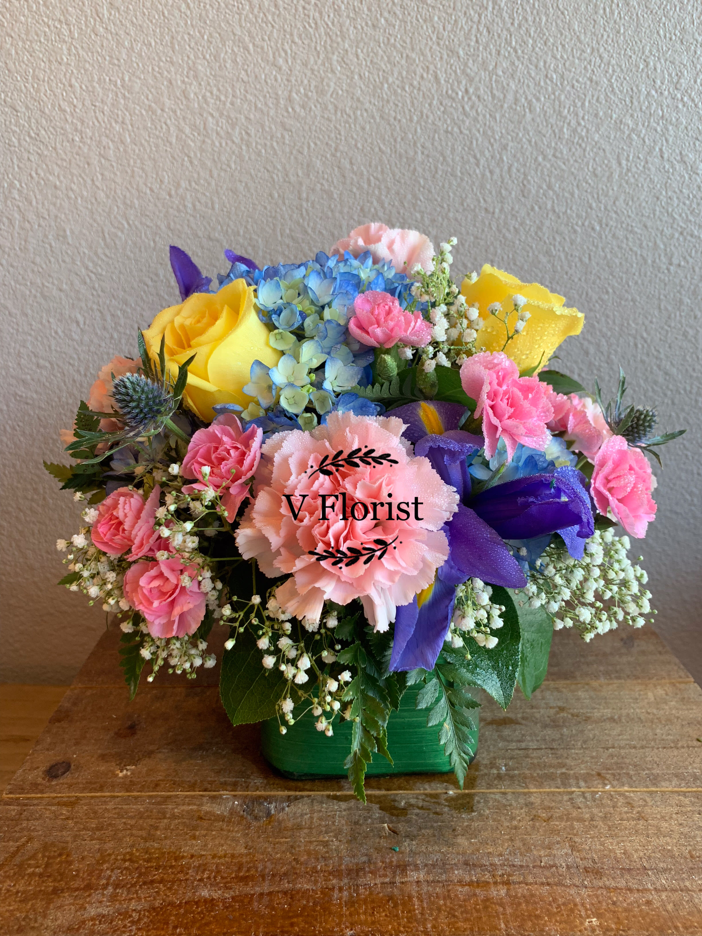 Spring Time Bouquet - Designer's choice of blue hydrangea, yellow roses, pink carnations, iris, and mini pink carnations in a cube vase.