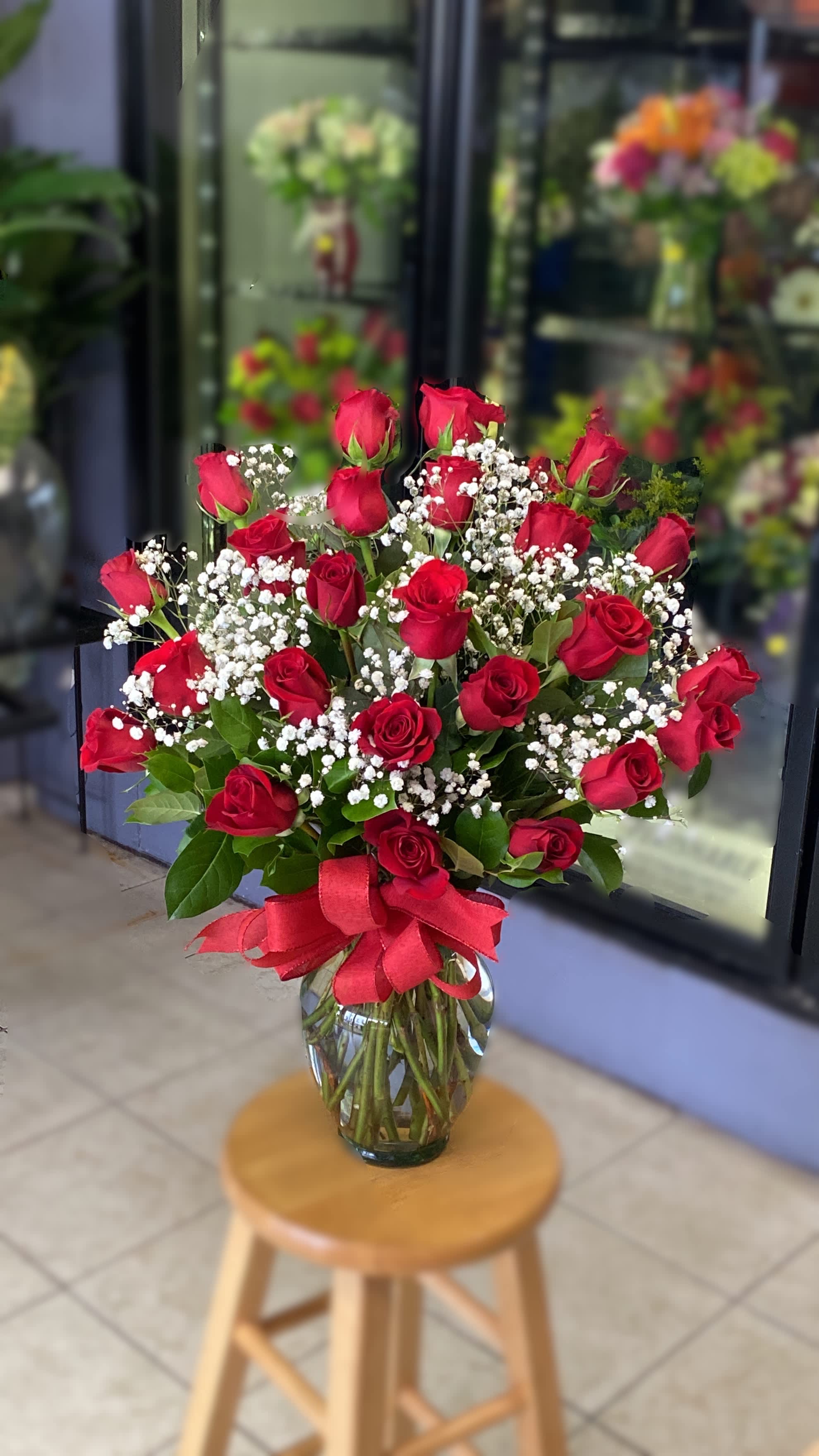 Bouquet of red roses and baby's breath in a glass vase with a red ribbon