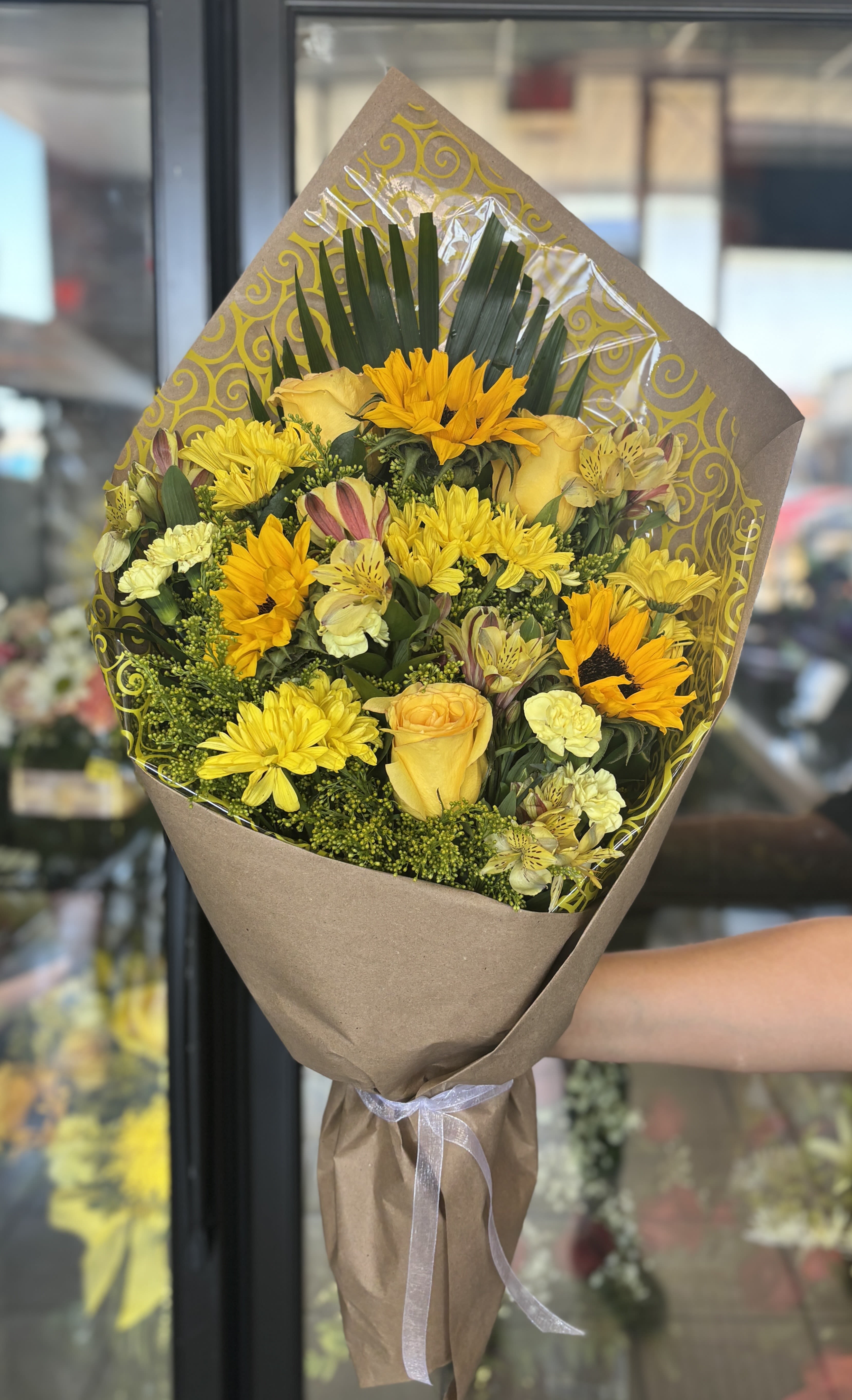 Yellow mixed bouquet wrapped in brown paper with a ribbon