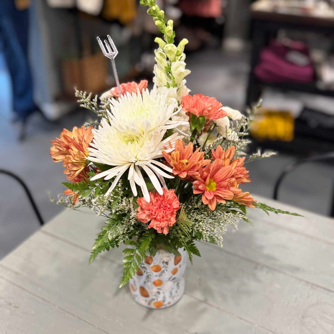 Mixed bouquet of white and coral flowers in a patterned vase